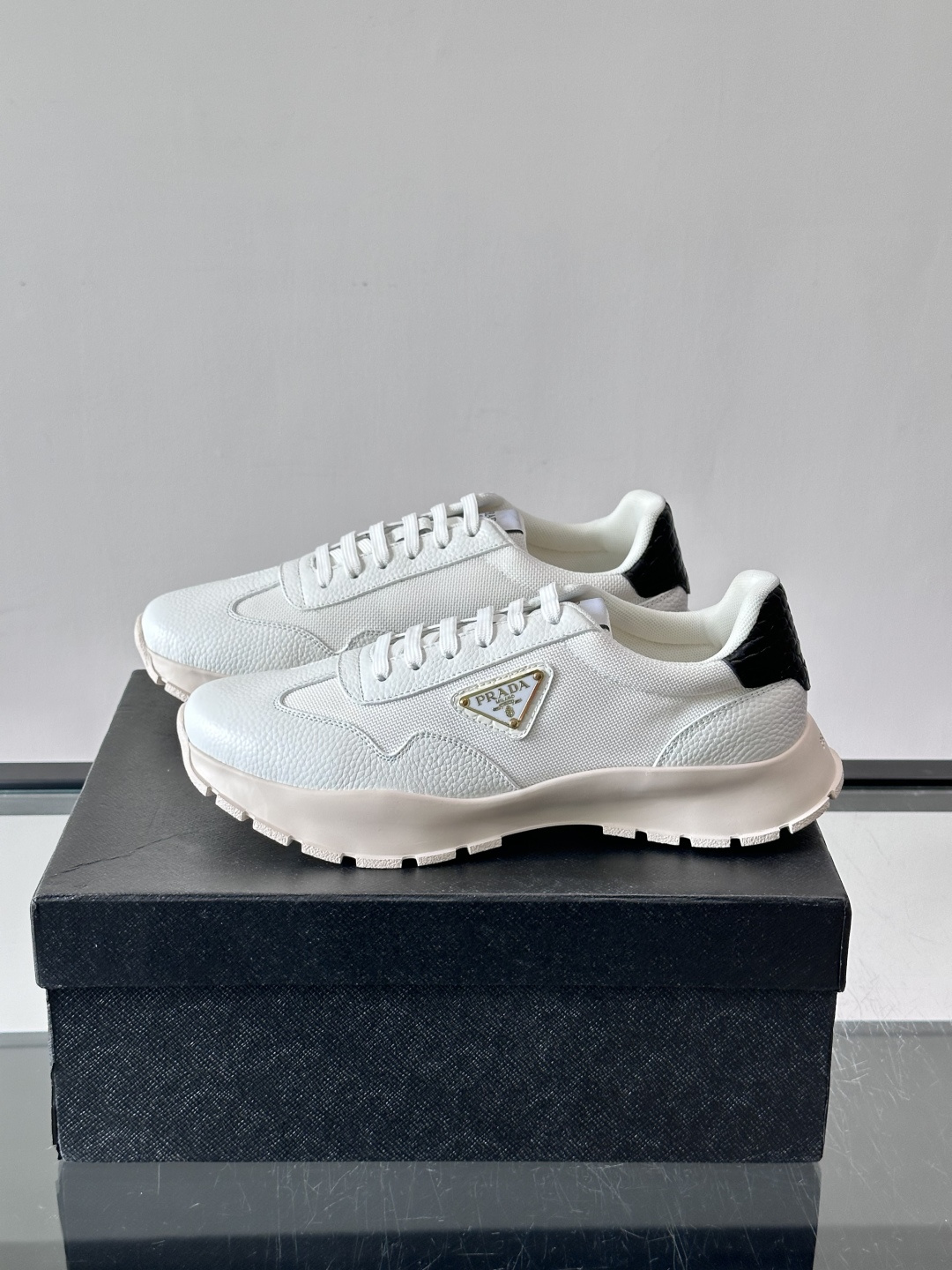 Prada 男士运动鞋,鞋面是荔枝纹皮革 + 网面拼接,鞋侧有金色三角形 Prada 徽标,质感上荔枝纹皮革的颗 Prada 男士运动鞋,鞋面是荔枝纹皮革 + 网面拼接,鞋侧有金色三角形 Prada 徽标,质感上荔枝纹皮革的颗