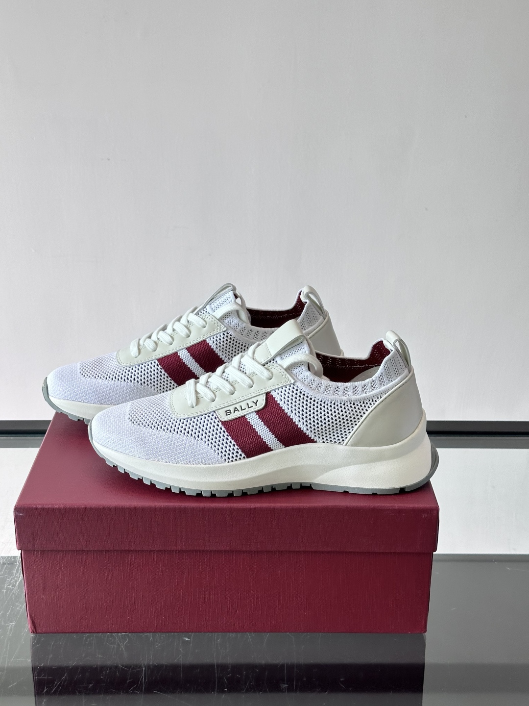 ​​BALLY（巴利）男士针织袜套鞋​​，飞织网面鞋身，一脚蹬的袜套式设计，厚底，鞋跟处有酒红色提环细节。这款走的是”轻