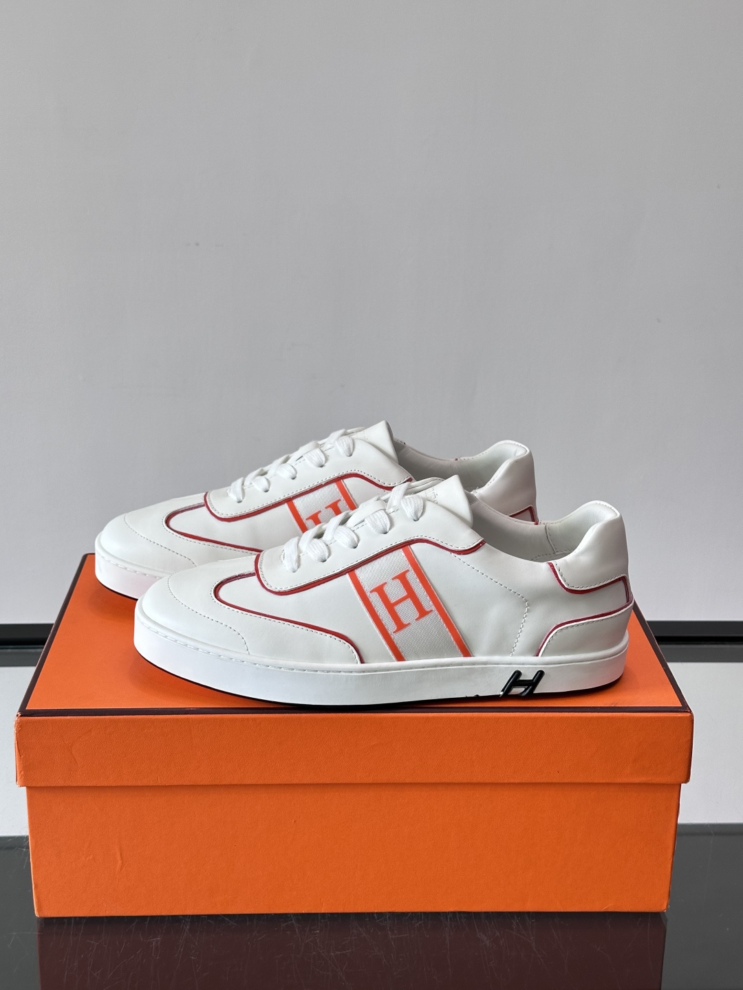 ​​Hermès 男士休闲运动鞋​​，皮革鞋面，鞋侧有橙色 H logo 织带装饰，白色橡胶鞋底。 In-the-Loo
