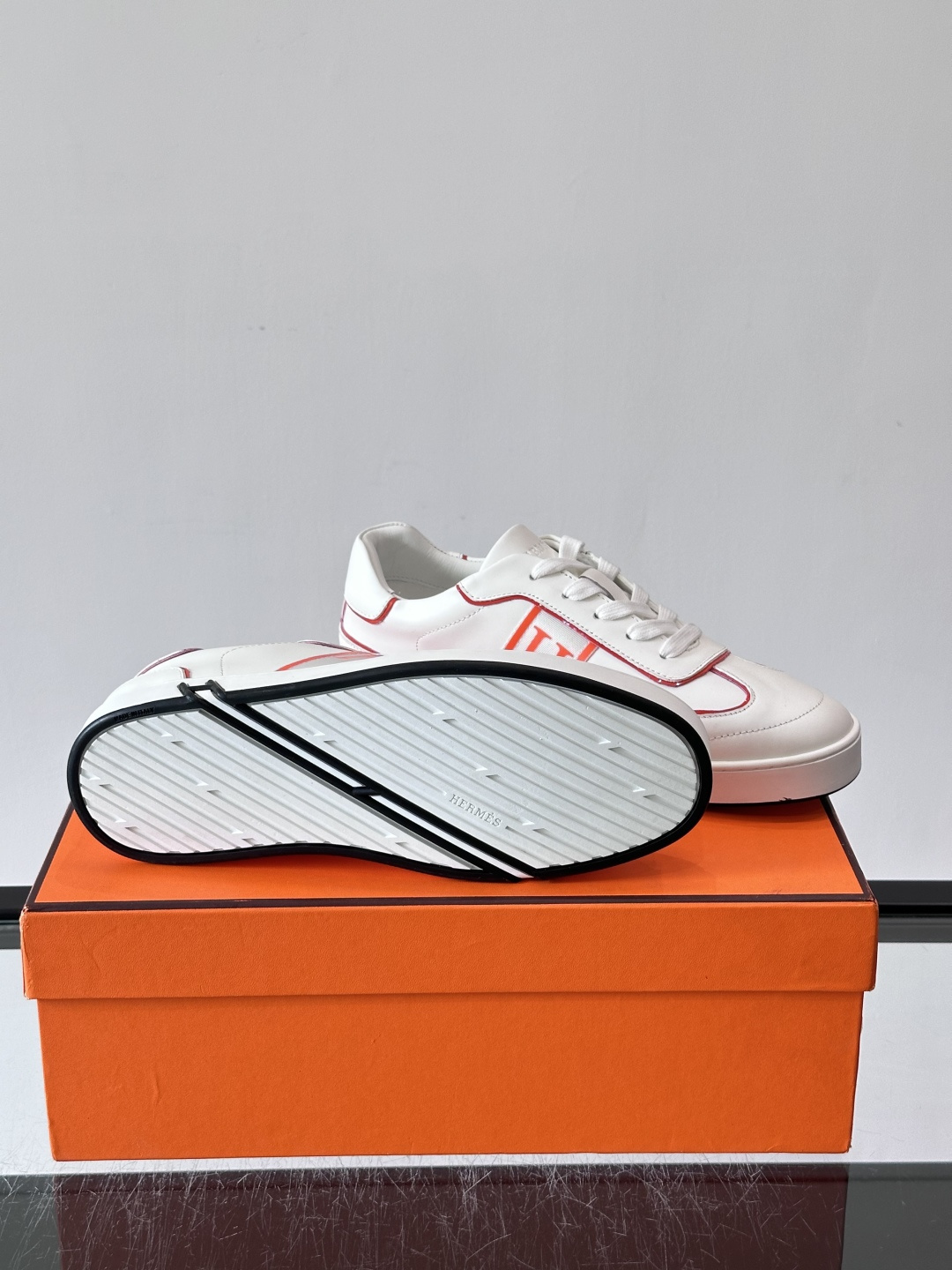 ​​Hermès 男士休闲运动鞋​​，皮革鞋面，鞋侧有橙色 H logo 织带装饰，白色橡胶鞋底。 In-the-Loo