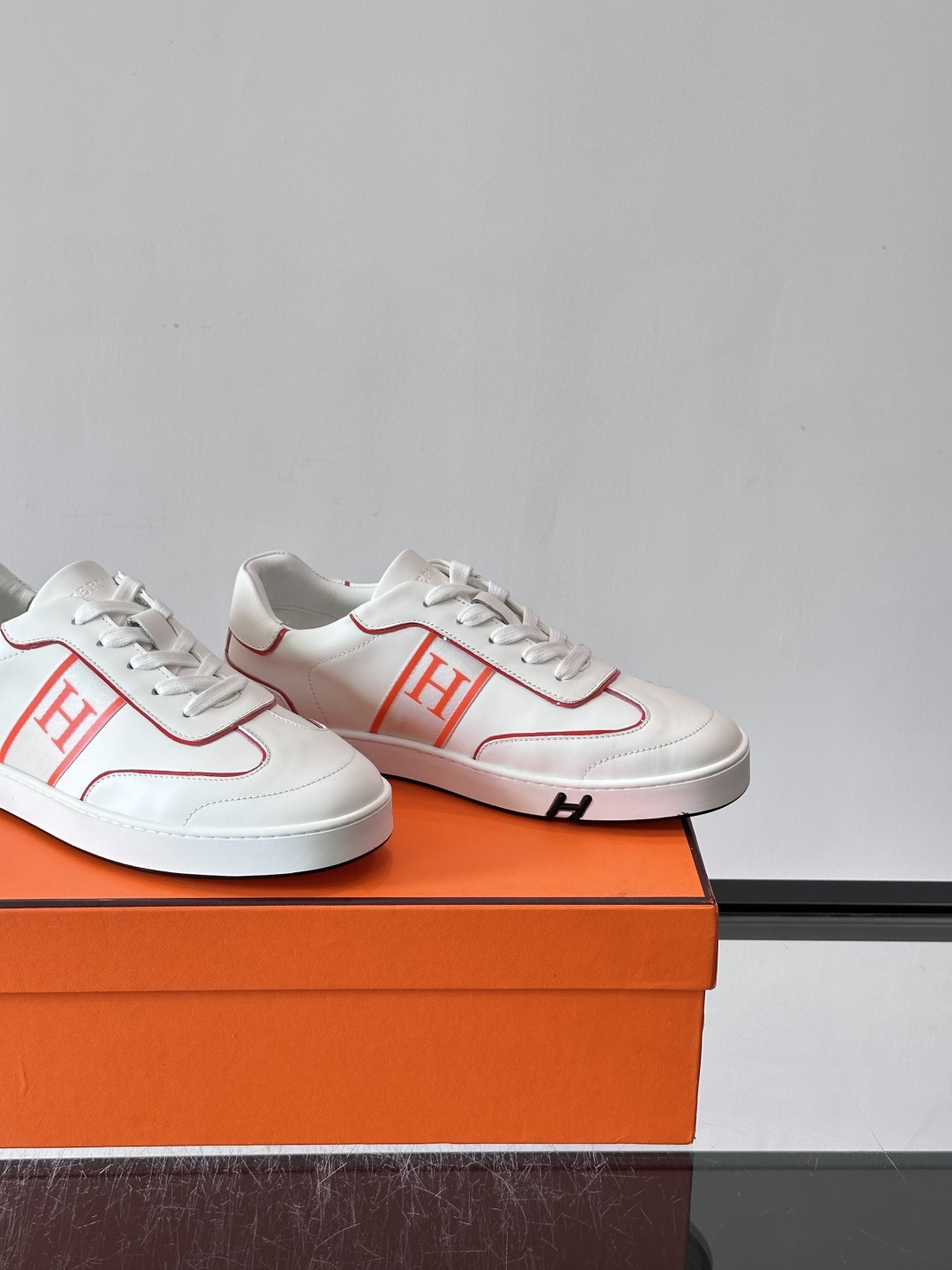 ​​Hermès 男士休闲运动鞋​​，皮革鞋面，鞋侧有橙色 H logo 织带装饰，白色橡胶鞋底。 In-the-Loo