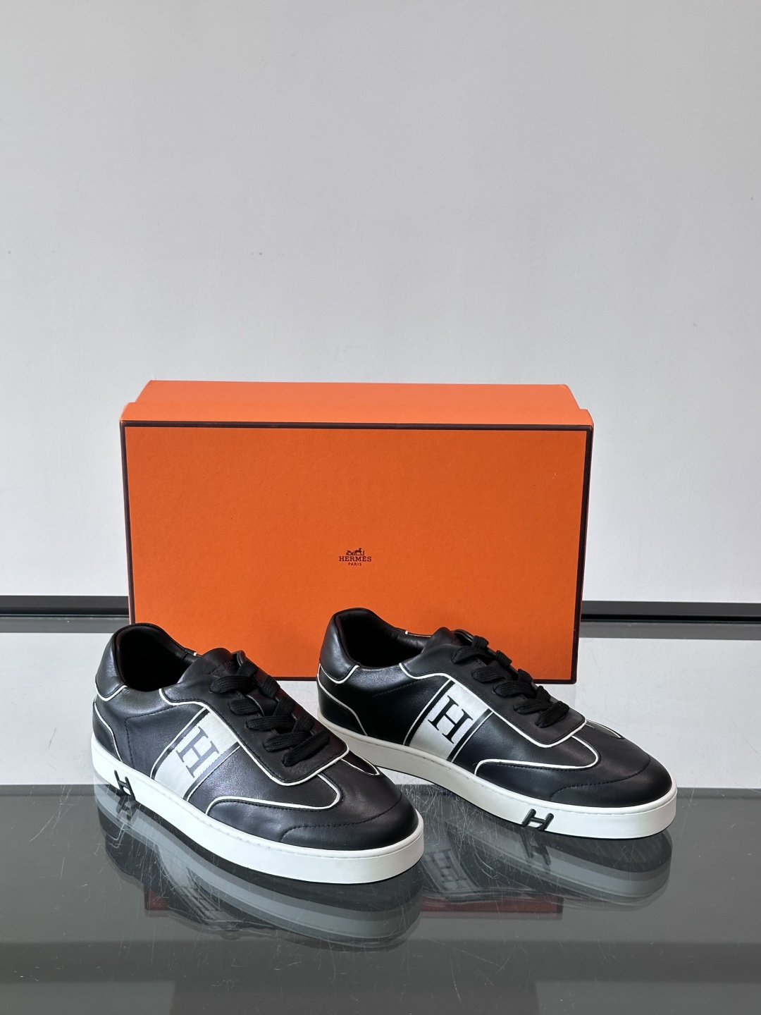 Hermès 男士休闲运动鞋,皮革鞋面,鞋侧有橙色 H logo 织带装饰,白色橡胶鞋底。 In-the-Loo Hermès 男士休闲运动鞋,皮革鞋面,鞋侧有橙色 H logo 织带装饰,白色橡胶鞋底。 In-the-Loo