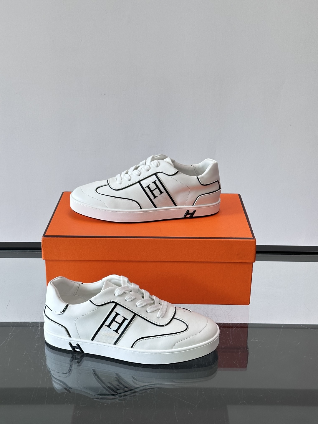 Hermès 男士休闲运动鞋,皮革鞋面,鞋侧有橙色 H logo 织带装饰,白色橡胶鞋底。 In-the-Loo Hermès 男士休闲运动鞋,皮革鞋面,鞋侧有橙色 H logo 织带装饰,白色橡胶鞋底。 In-the-Loo