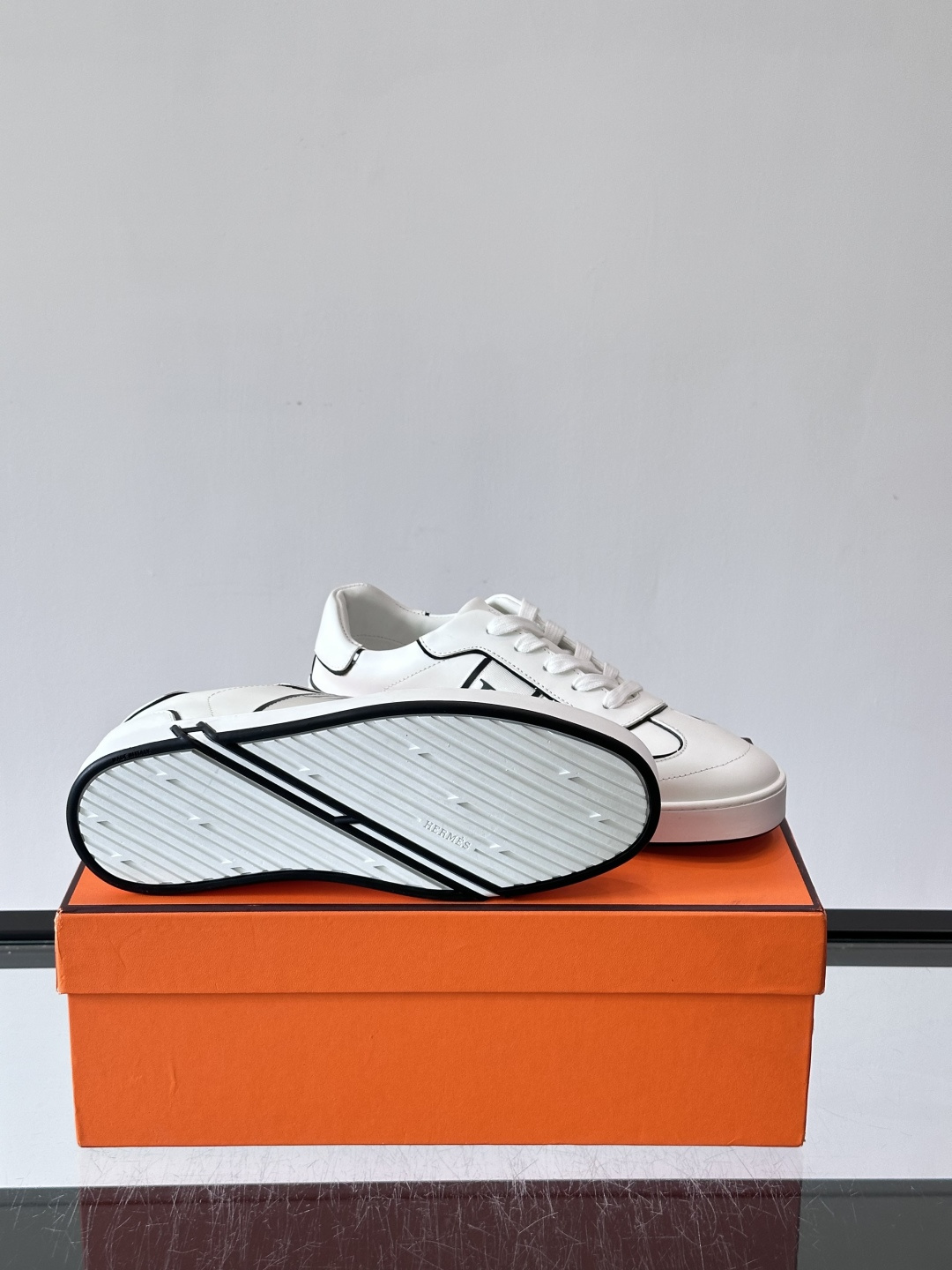 Hermès 男士休闲运动鞋,皮革鞋面,鞋侧有橙色 H logo 织带装饰,白色橡胶鞋底。 In-the-Loo Hermès 男士休闲运动鞋,皮革鞋面,鞋侧有橙色 H logo 织带装饰,白色橡胶鞋底。 In-the-Loo