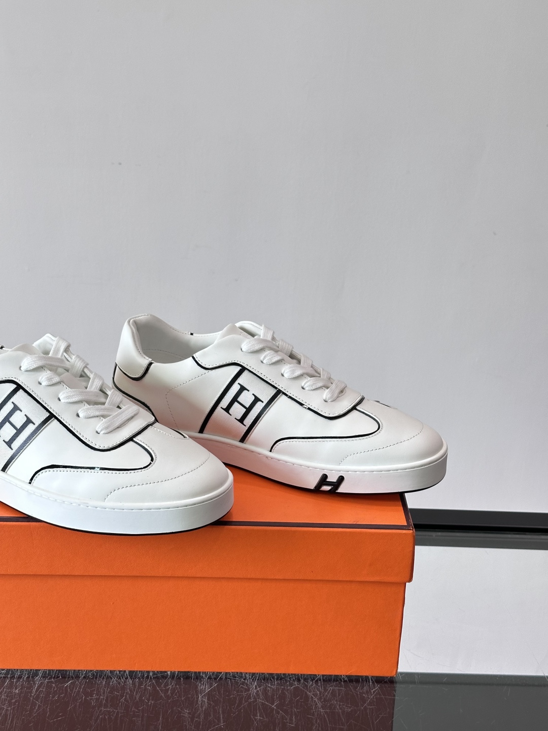 Hermès 男士休闲运动鞋,皮革鞋面,鞋侧有橙色 H logo 织带装饰,白色橡胶鞋底。 In-the-Loo Hermès 男士休闲运动鞋,皮革鞋面,鞋侧有橙色 H logo 织带装饰,白色橡胶鞋底。 In-the-Loo