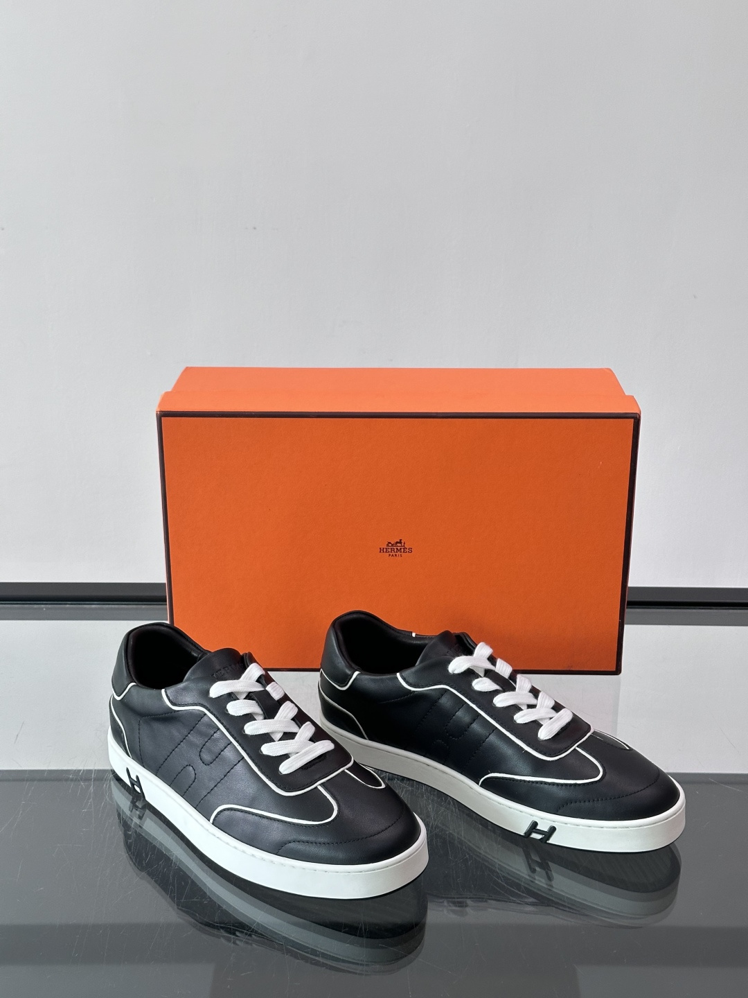 Hermès 男士休闲运动鞋,皮革鞋面,鞋侧有橙色 H logo 织带装饰,白色橡胶鞋底。 In-the-Loo Hermès 男士休闲运动鞋,皮革鞋面,鞋侧有橙色 H logo 织带装饰,白色橡胶鞋底。 In-the-Loo