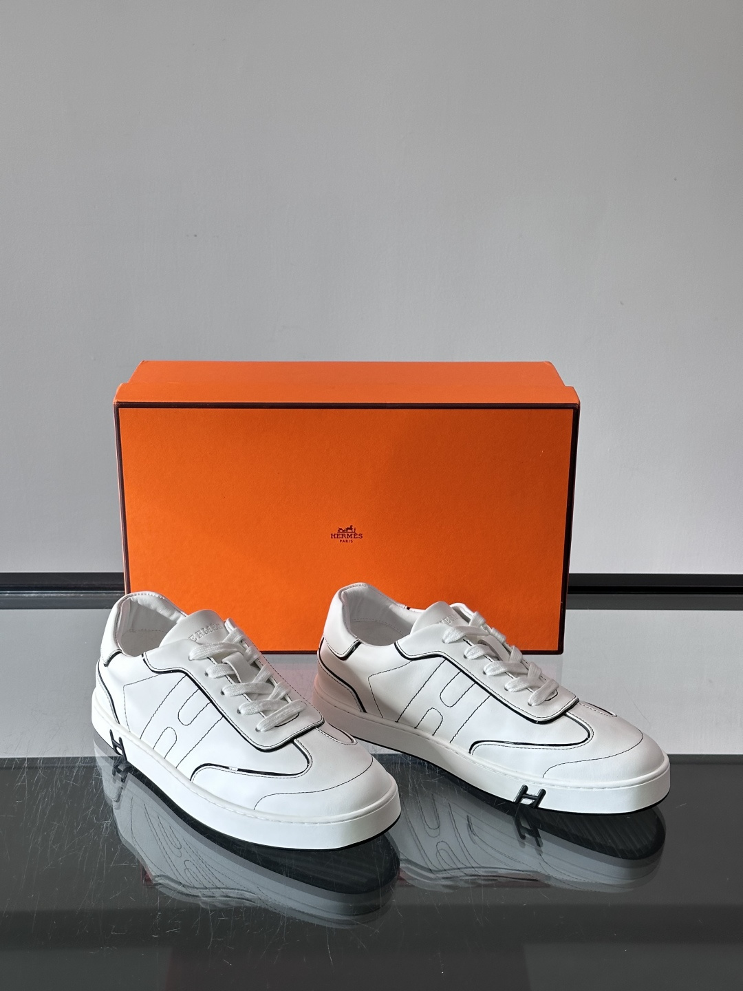 Hermès 男士休闲运动鞋,皮革鞋面,鞋侧有橙色 H logo 织带装饰,白色橡胶鞋底。 In-the-Loo Hermès 男士休闲运动鞋,皮革鞋面,鞋侧有橙色 H logo 织带装饰,白色橡胶鞋底。 In-the-Loo