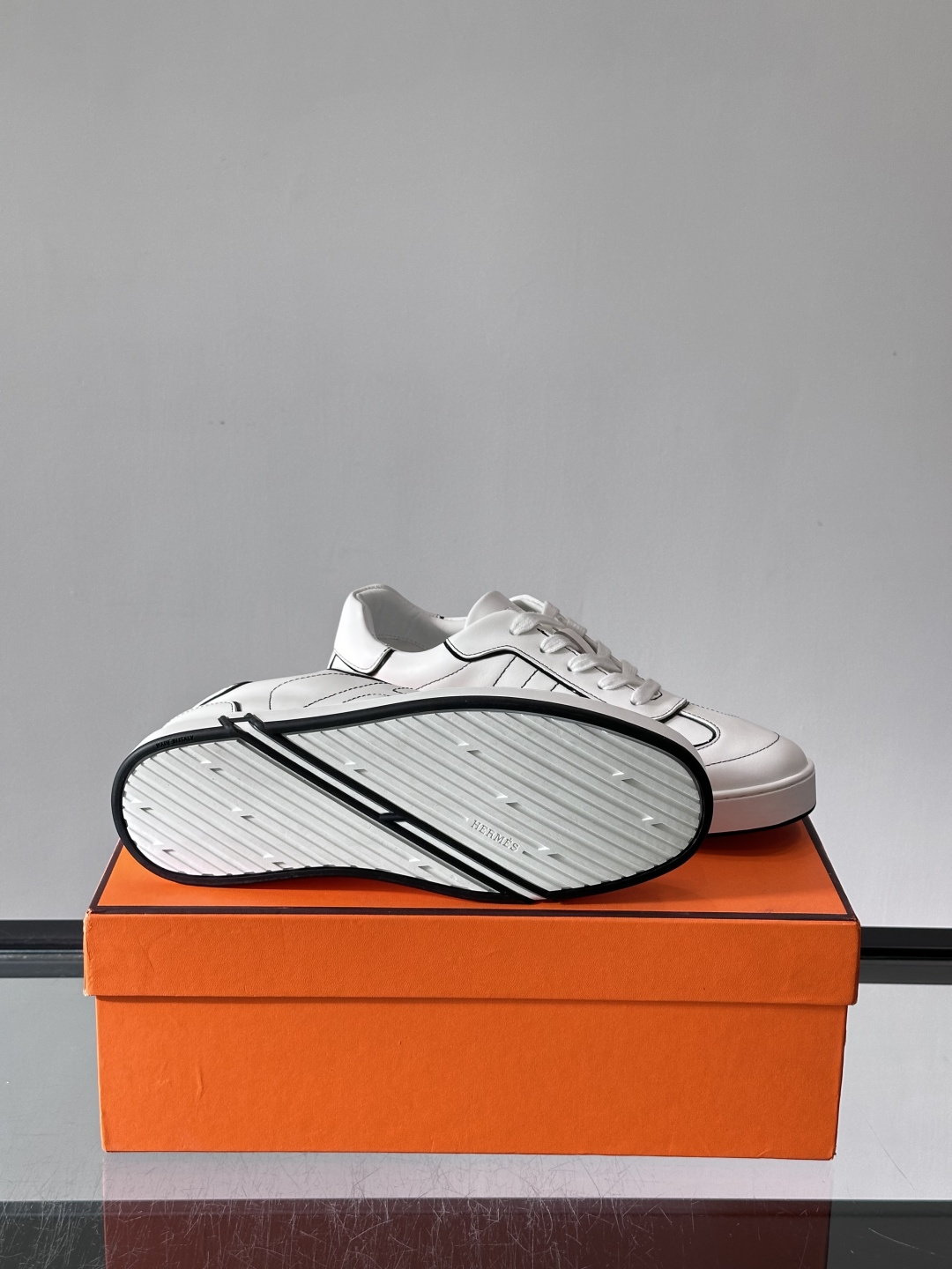 Hermès 男士休闲运动鞋,皮革鞋面,鞋侧有橙色 H logo 织带装饰,白色橡胶鞋底。 In-the-Loo Hermès 男士休闲运动鞋,皮革鞋面,鞋侧有橙色 H logo 织带装饰,白色橡胶鞋底。 In-the-Loo