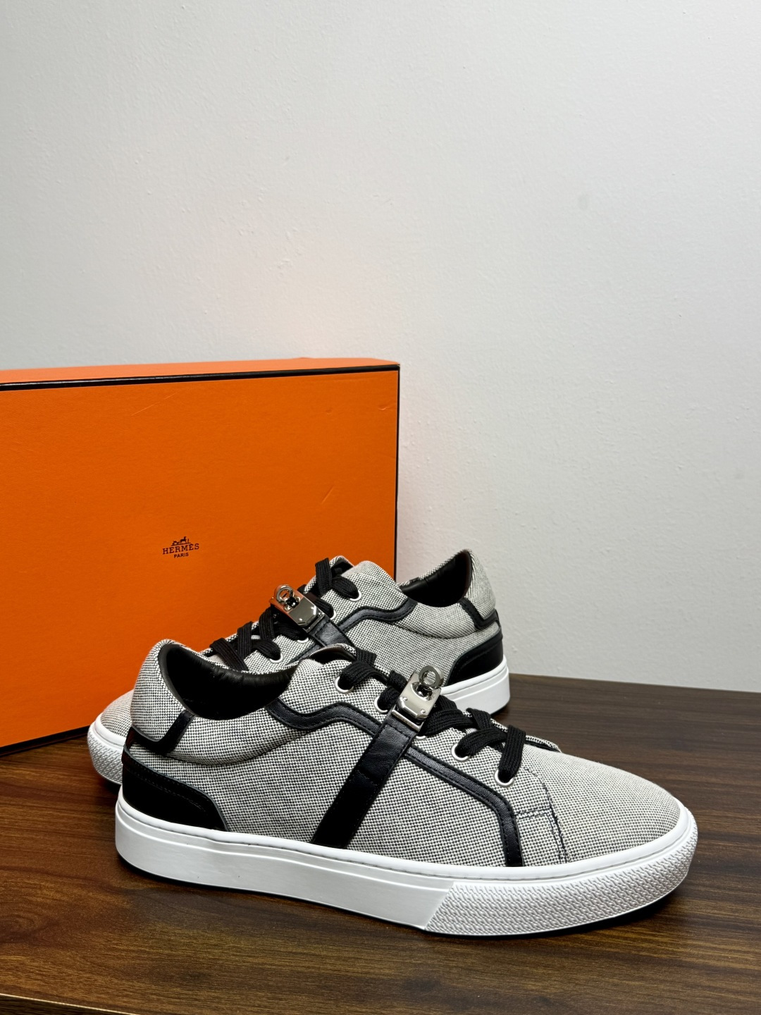 Hermès Kelly扣帆布板鞋​，鞋面是灰色H帆布 + 小牛皮拼接，最大辨识点是鞋带上那颗 ​​镀钯Kelly金属锁