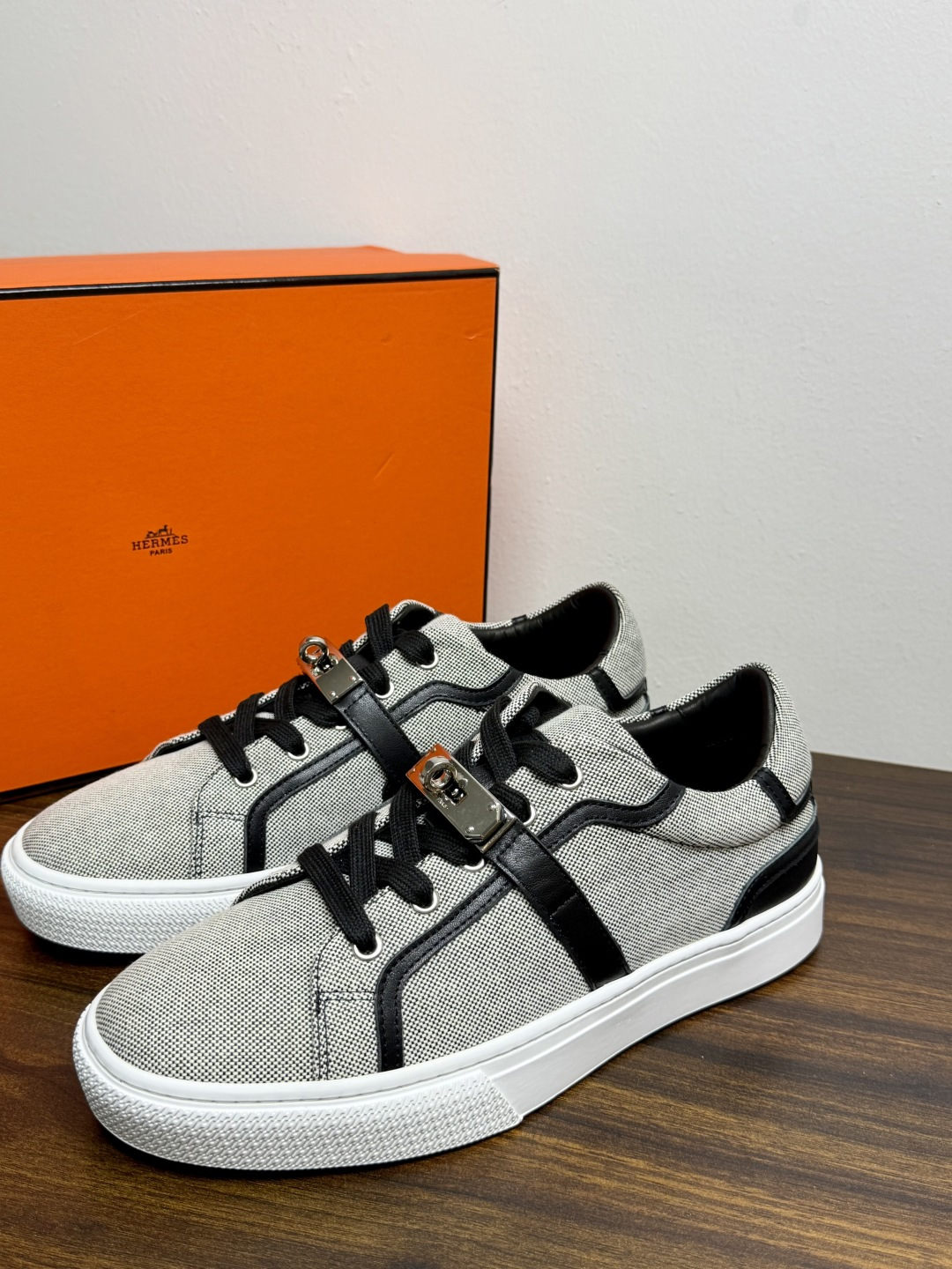 Hermès Kelly扣帆布板鞋​，鞋面是灰色H帆布 + 小牛皮拼接，最大辨识点是鞋带上那颗 ​​镀钯Kelly金属锁