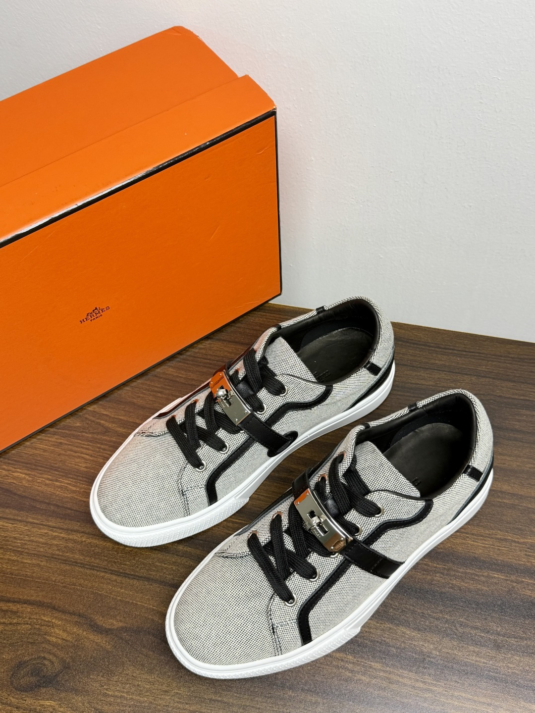 Hermès Kelly扣帆布板鞋​，鞋面是灰色H帆布 + 小牛皮拼接，最大辨识点是鞋带上那颗 ​​镀钯Kelly金属锁