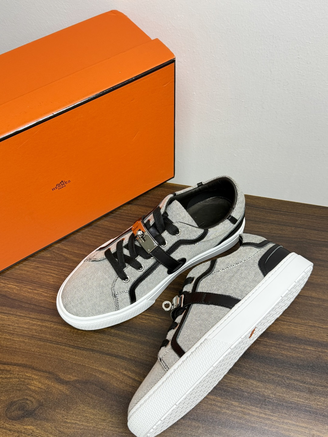 Hermès Kelly扣帆布板鞋​，鞋面是灰色H帆布 + 小牛皮拼接，最大辨识点是鞋带上那颗 ​​镀钯Kelly金属锁