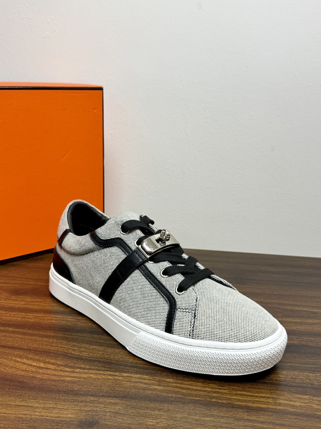 Hermès Kelly扣帆布板鞋​，鞋面是灰色H帆布 + 小牛皮拼接，最大辨识点是鞋带上那颗 ​​镀钯Kelly金属锁