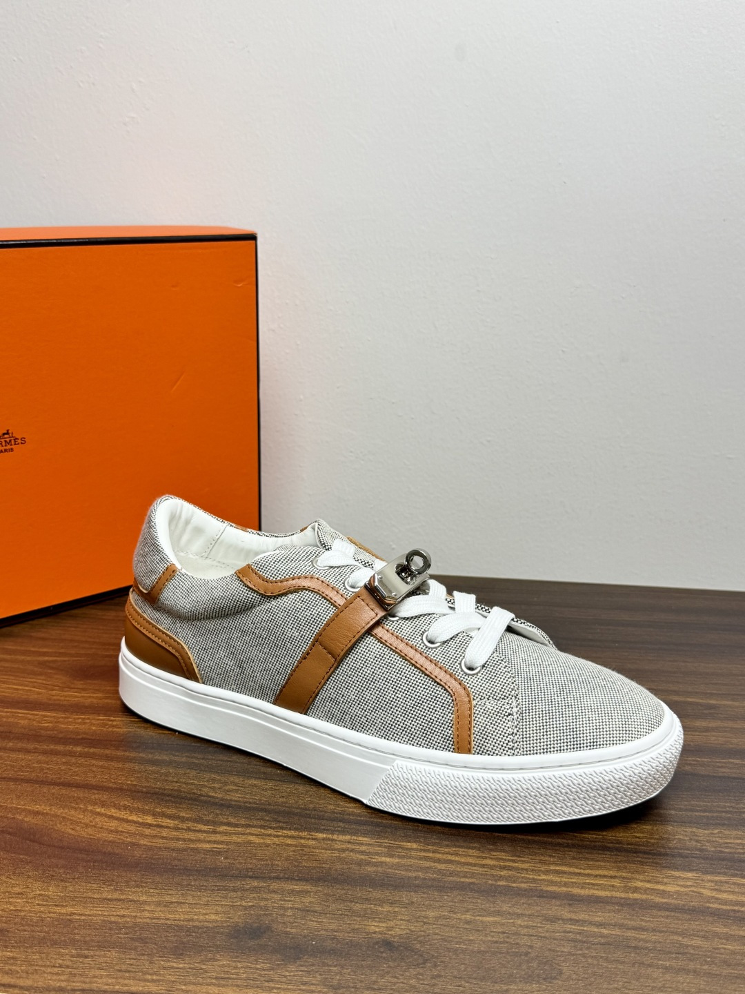 Hermès Kelly扣帆布板鞋​，鞋面是灰色H帆布 + 小牛皮拼接，最大辨识点是鞋带上那颗 ​​镀钯Kelly金属锁