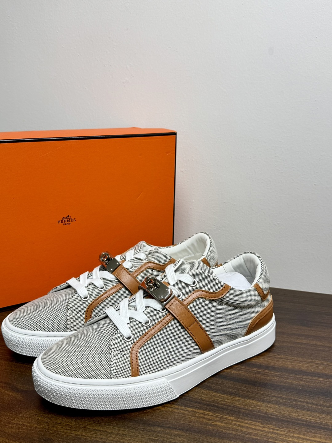 Hermès Kelly扣帆布板鞋​，鞋面是灰色H帆布 + 小牛皮拼接，最大辨识点是鞋带上那颗 ​​镀钯Kelly金属锁