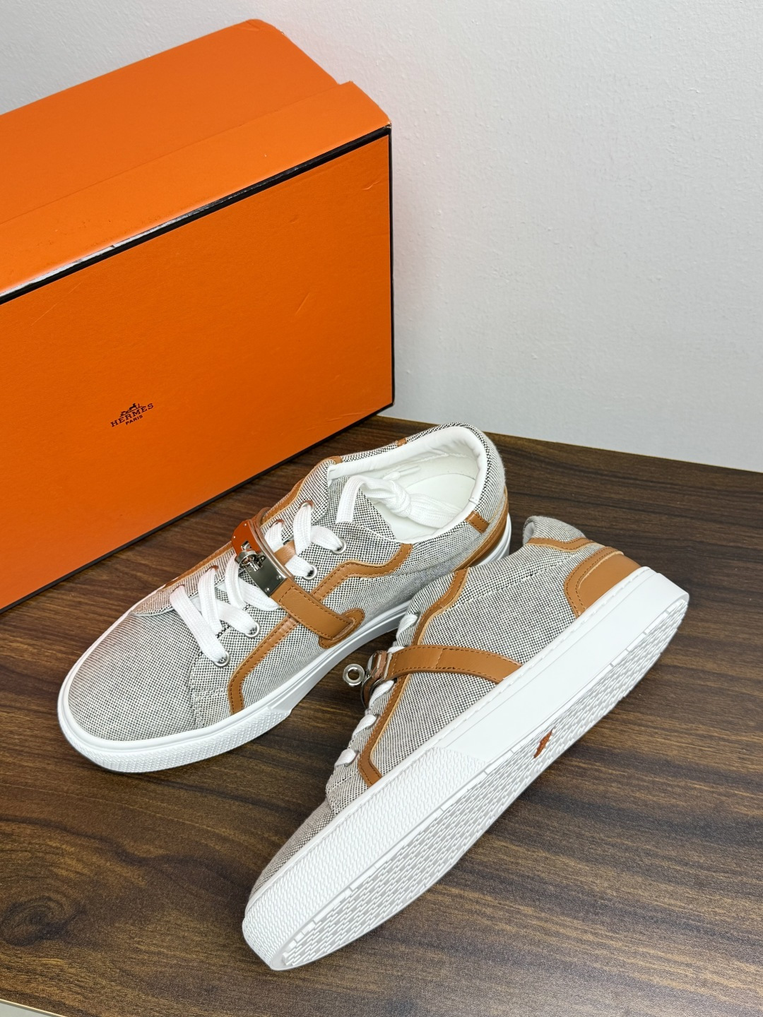 Hermès Kelly扣帆布板鞋​，鞋面是灰色H帆布 + 小牛皮拼接，最大辨识点是鞋带上那颗 ​​镀钯Kelly金属锁