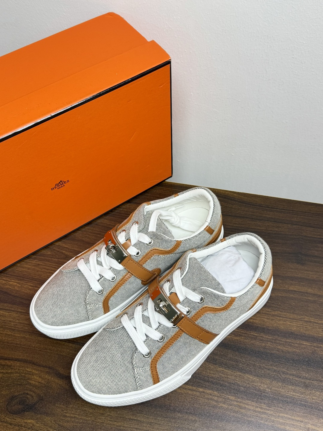 Hermès Kelly扣帆布板鞋​，鞋面是灰色H帆布 + 小牛皮拼接，最大辨识点是鞋带上那颗 ​​镀钯Kelly金属锁