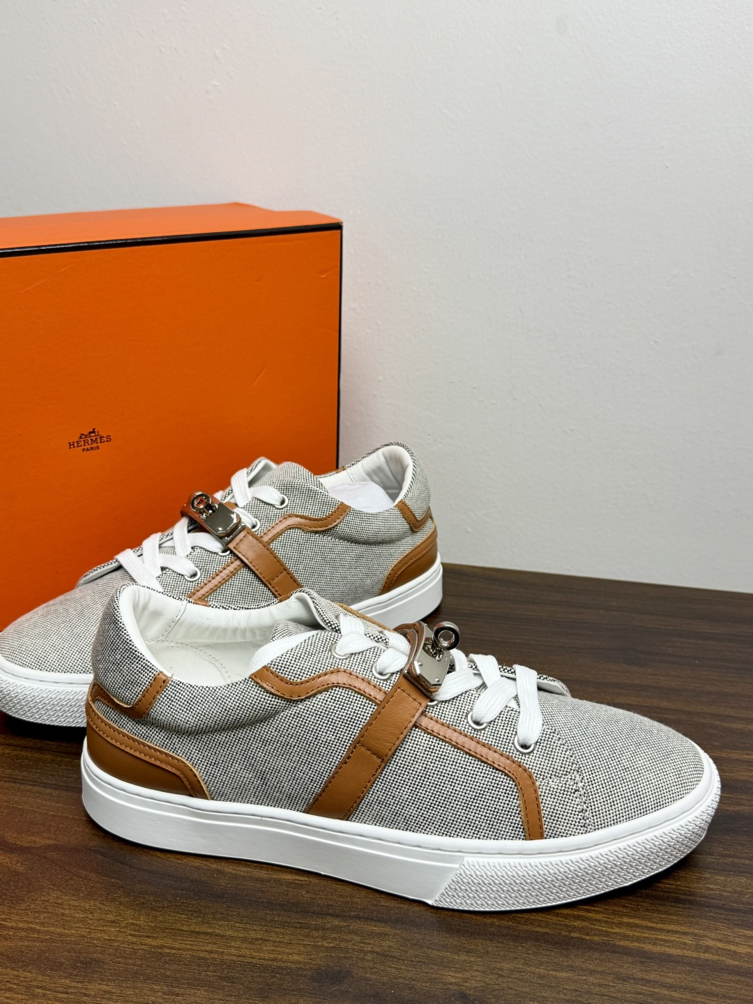 Hermès Kelly扣帆布板鞋​，鞋面是灰色H帆布 + 小牛皮拼接，最大辨识点是鞋带上那颗 ​​镀钯Kelly金属锁