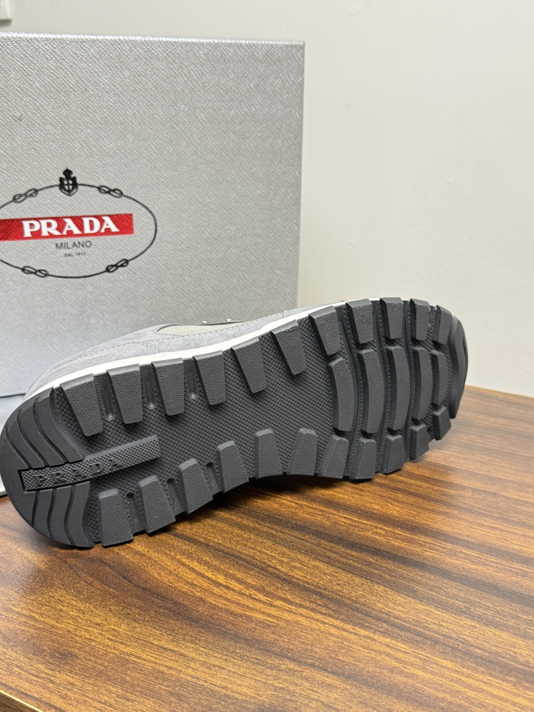 Prada Brush 运动鞋​​，鞋面是麂皮 + 尼龙织物拼接，侧面有 Prada 标志性的 三角珐琅金属标 ，厚底橡
