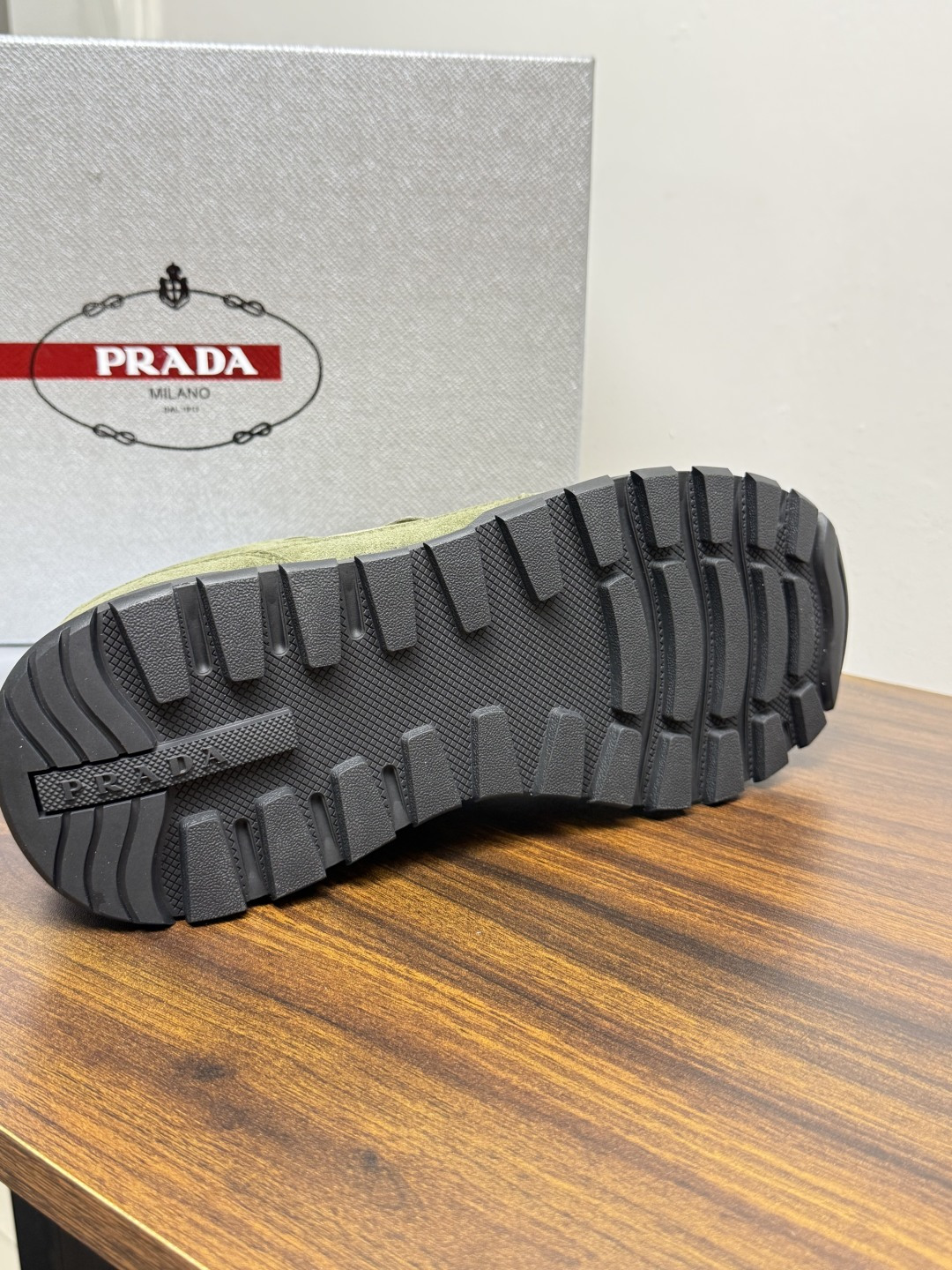 Prada Brush 运动鞋​​，鞋面是麂皮 + 尼龙织物拼接，侧面有 Prada 标志性的 三角珐琅金属标 ，厚底橡
