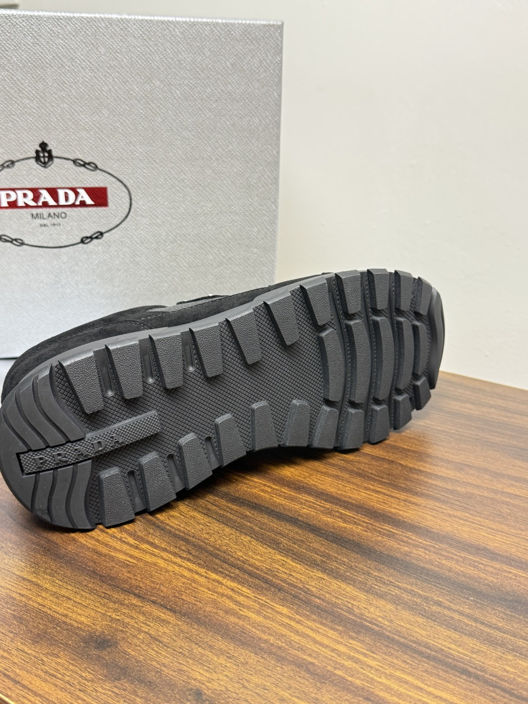 Prada Brush 运动鞋​​，鞋面是麂皮 + 尼龙织物拼接，侧面有 Prada 标志性的 三角珐琅金属标 ，厚底橡