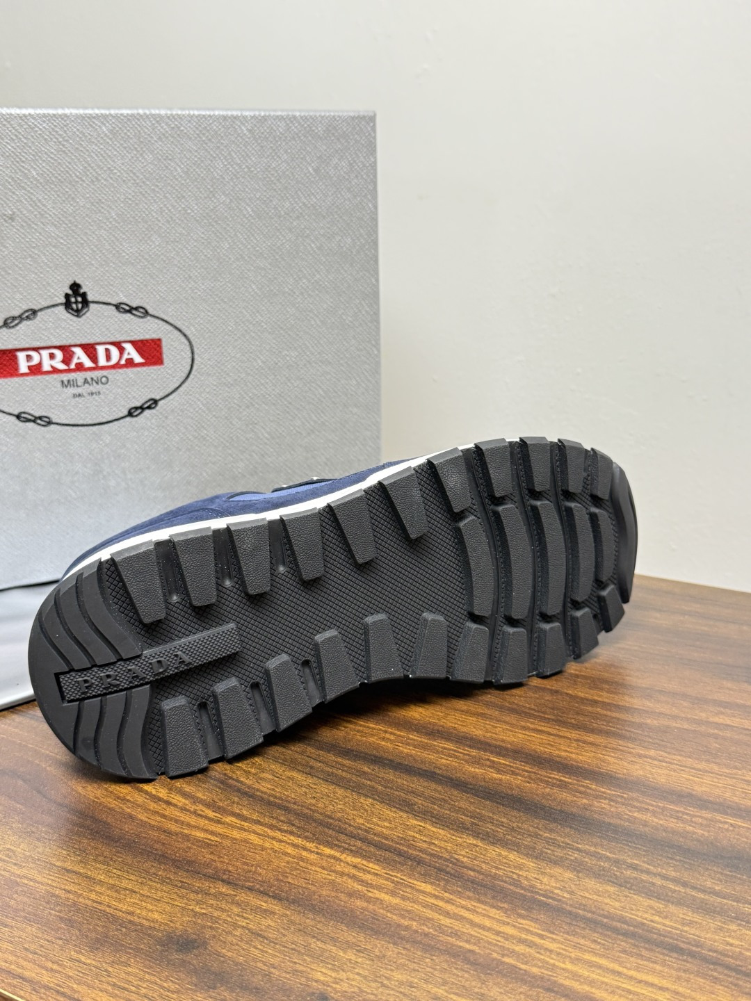 Prada Brush 运动鞋​​，鞋面是麂皮 + 尼龙织物拼接，侧面有 Prada 标志性的 三角珐琅金属标 ，厚底橡