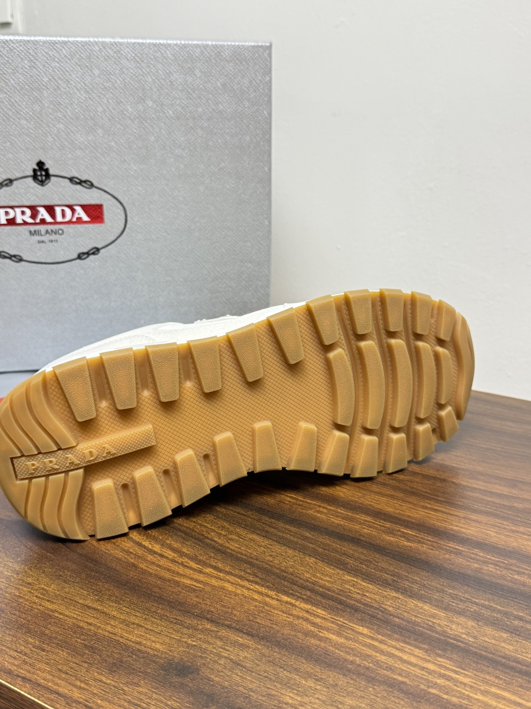 Prada Brush 运动鞋​​，鞋面是麂皮 + 尼龙织物拼接，侧面有 Prada 标志性的 三角珐琅金属标 ，厚底橡