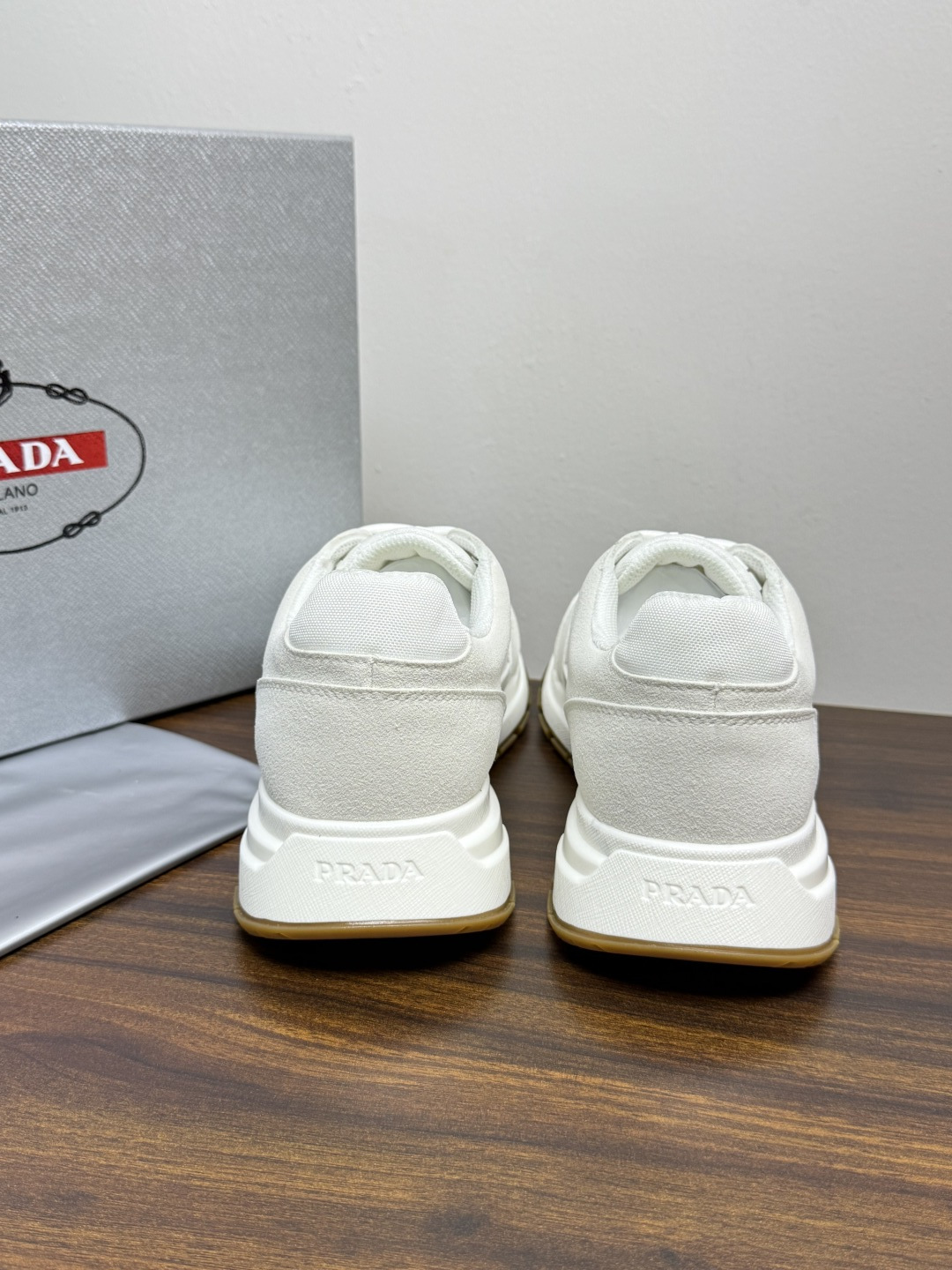 Prada Brush 运动鞋​​，鞋面是麂皮 + 尼龙织物拼接，侧面有 Prada 标志性的 三角珐琅金属标 ，厚底橡