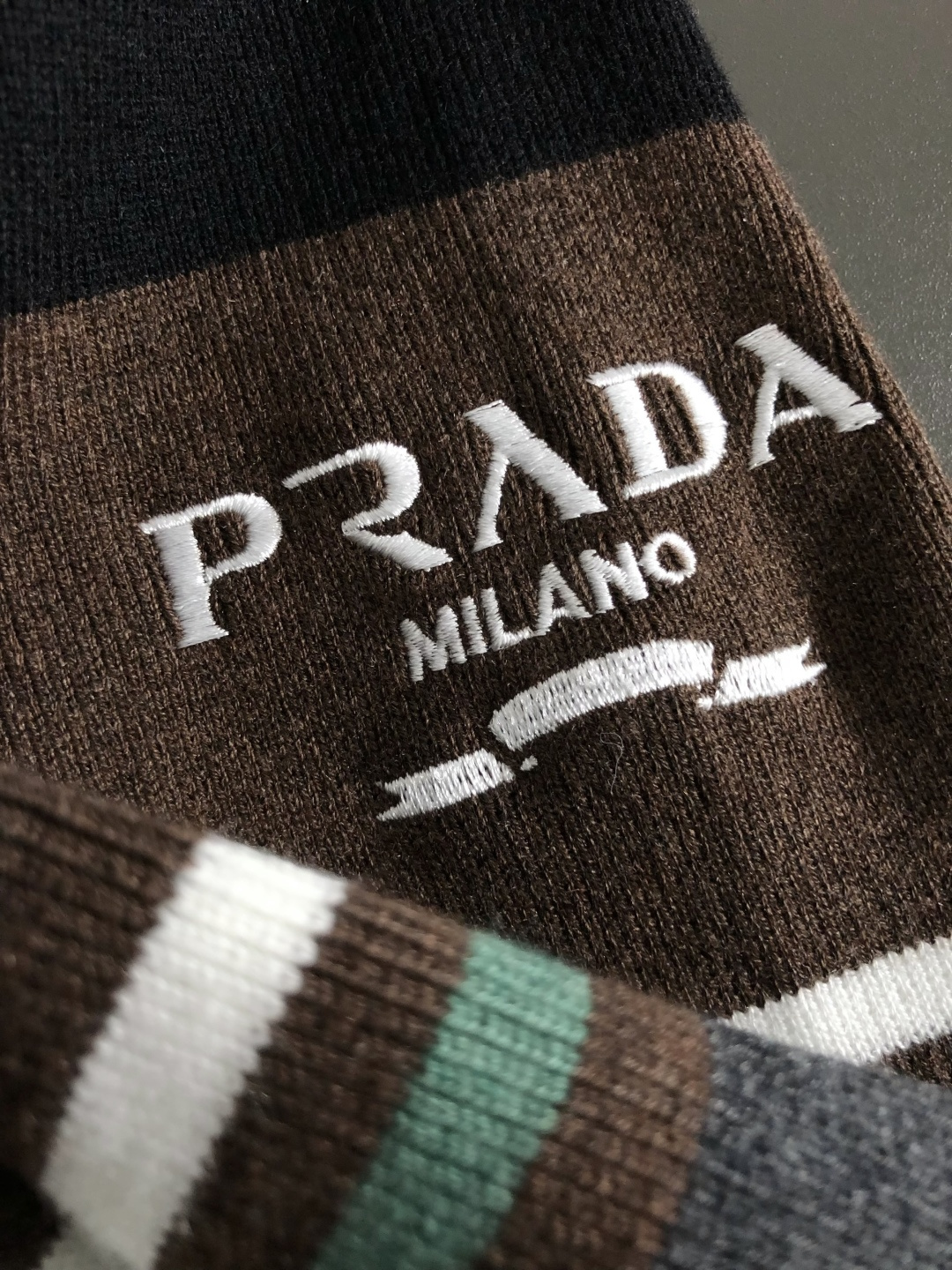 Prad*合身版型M-XXXl2025秋冬潮牌羊毛衫，以双领口皮绳搭配点缀为主调，巧妙袖子多色撞色提花字