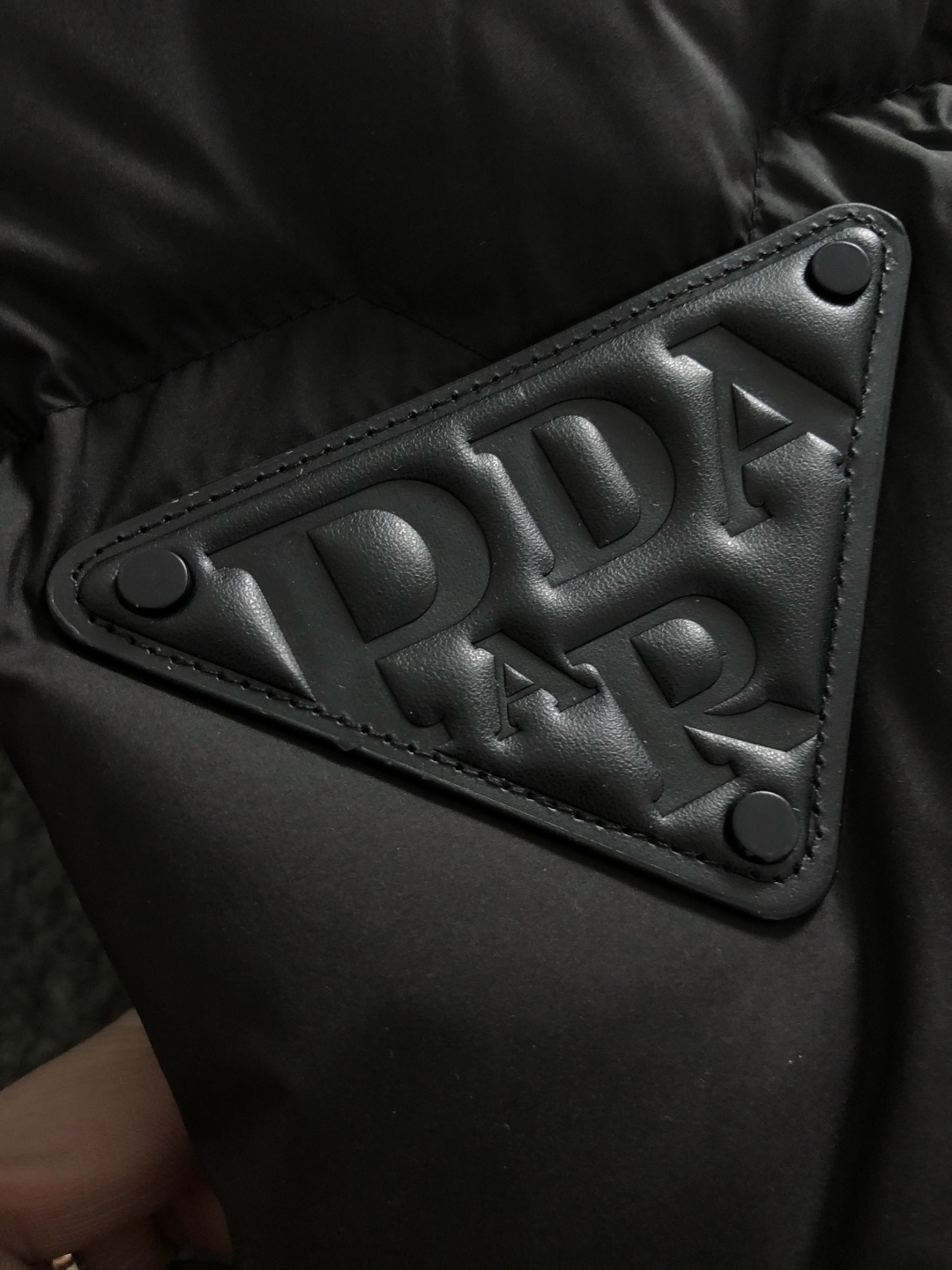 Prad*合身版型48-562025秋冬90白鸭绒羽绒马甲，以真皮贴皮元素点缀为主调，融入贴皮三角标元素