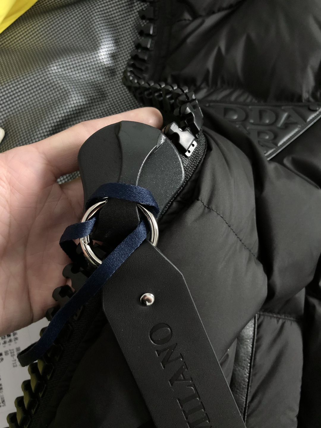 Prad*合身版型48-562025秋冬90白鸭绒羽绒马甲，以真皮贴皮元素点缀为主调，融入贴皮三角标元素