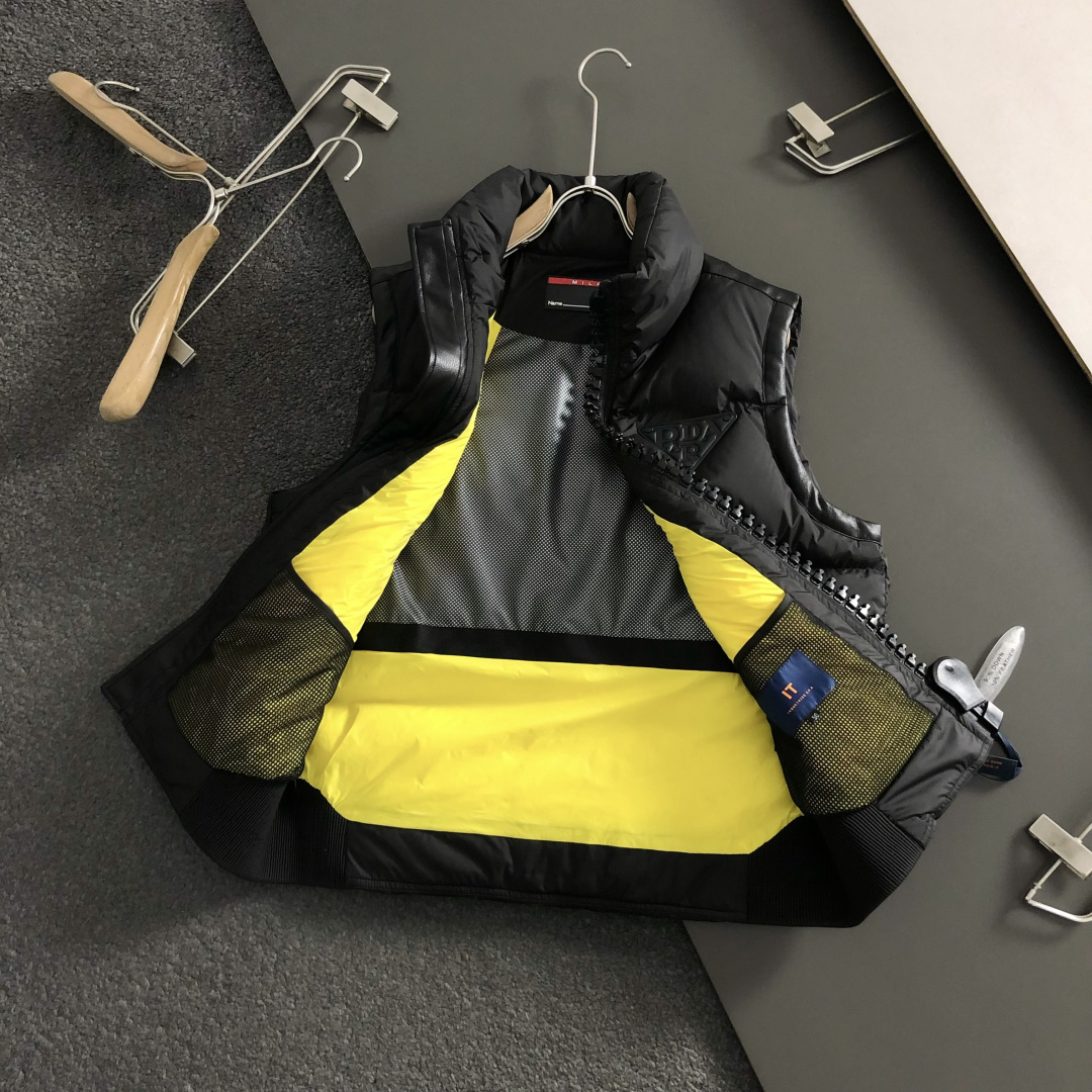 Prad*合身版型48-562025秋冬90白鸭绒羽绒马甲，以真皮贴皮元素点缀为主调，融入贴皮三角标元素