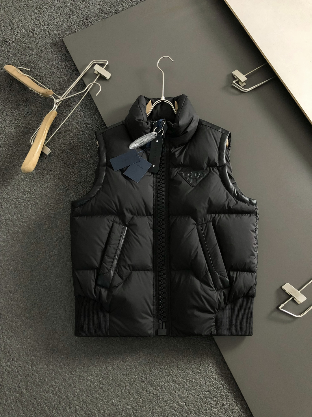 Prad*合身版型48-562025秋冬90白鸭绒羽绒马甲，以真皮贴皮元素点缀为主调，融入贴皮三角标元素