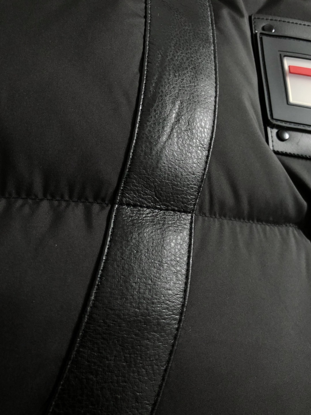 Prad*合身版型48-562025秋冬90白鸭绒羽绒马甲，以真皮贴皮元素点缀为主调，融入贴皮三角标元素