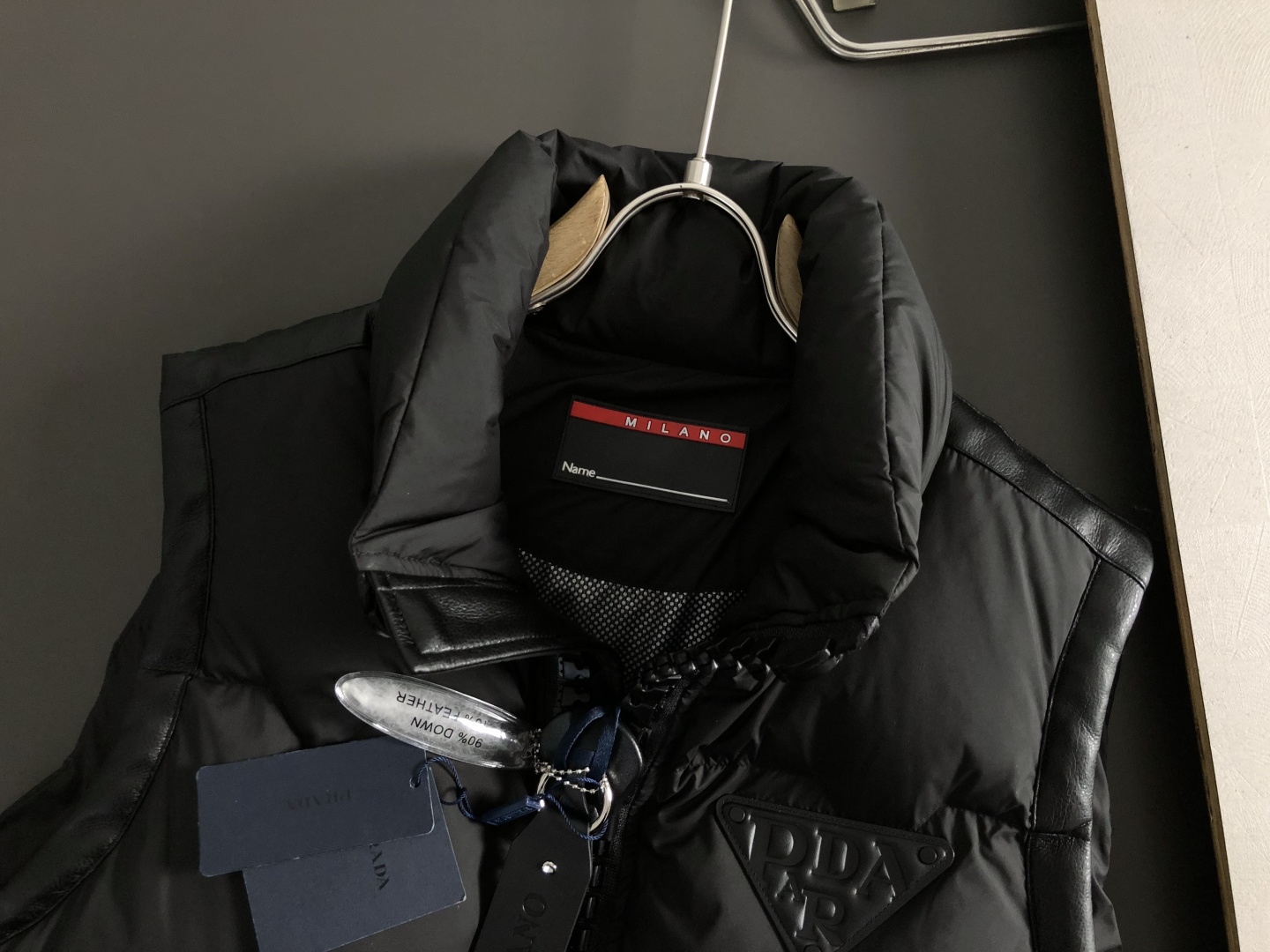 Prad*合身版型48-562025秋冬90白鸭绒羽绒马甲，以真皮贴皮元素点缀为主调，融入贴皮三角标元素