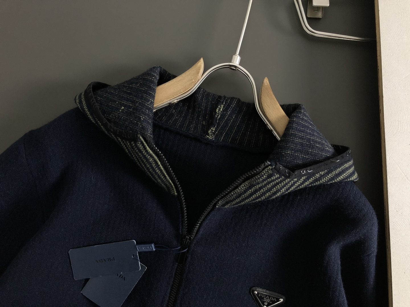 Prad*微宽版型M-XXXl2025秋冬潮牌针织开衫，以金属三角标点缀为主调，巧妙融入坑条撞色螺纹领拼