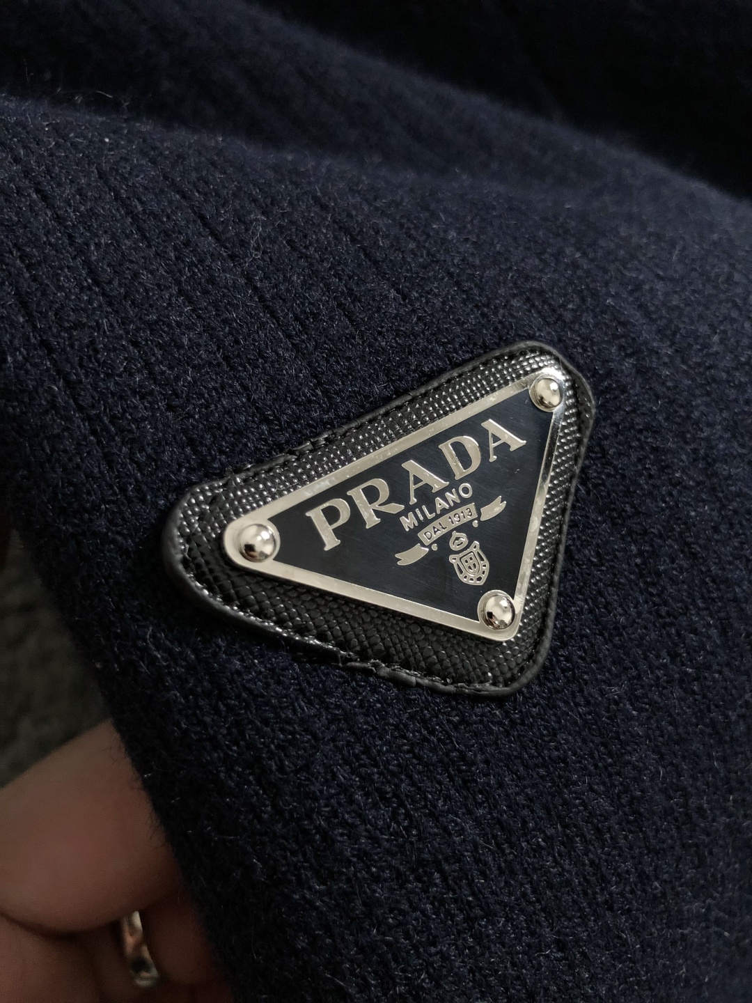 Prad*微宽版型M-XXXl2025秋冬潮牌针织开衫，以金属三角标点缀为主调，巧妙融入坑条撞色螺纹领拼