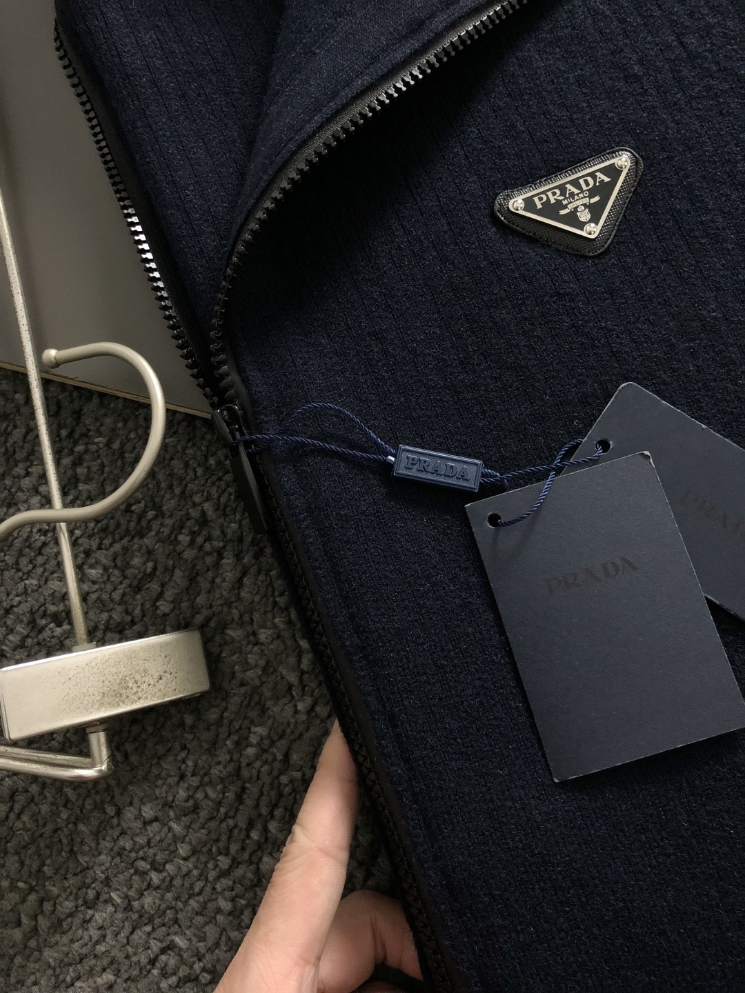 Prad*微宽版型M-XXXl2025秋冬潮牌针织开衫，以金属三角标点缀为主调，巧妙融入坑条撞色螺纹领拼