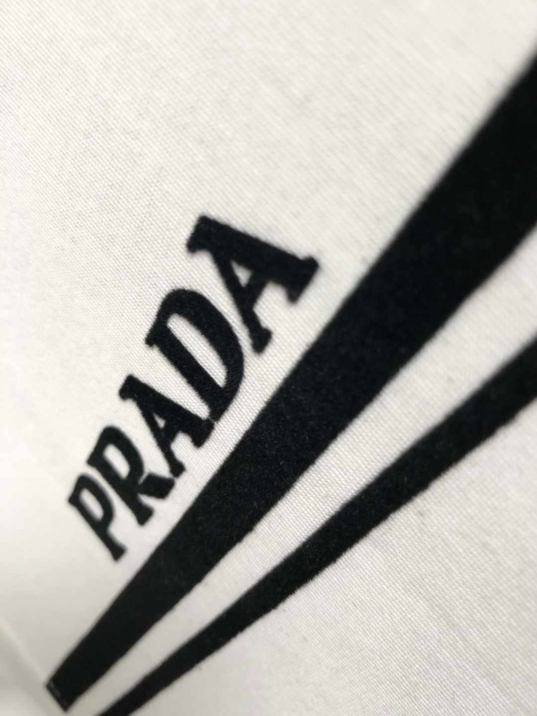 Prad*正码正拍M-xxxl2026春夏短袖，以黑白撞色为主调，巧妙融入植绒线条印花金属三角标元素，打