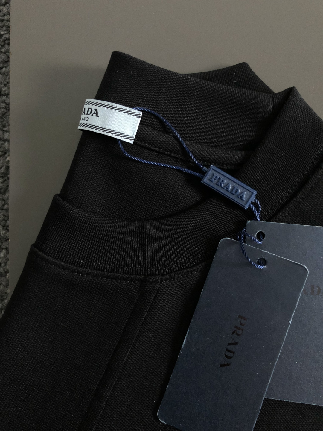 Prad*卡码拍小M-xxxl2026春夏短袖，以金属三角标口袋主调，巧妙融入后幅拼接面料元素，打破传统