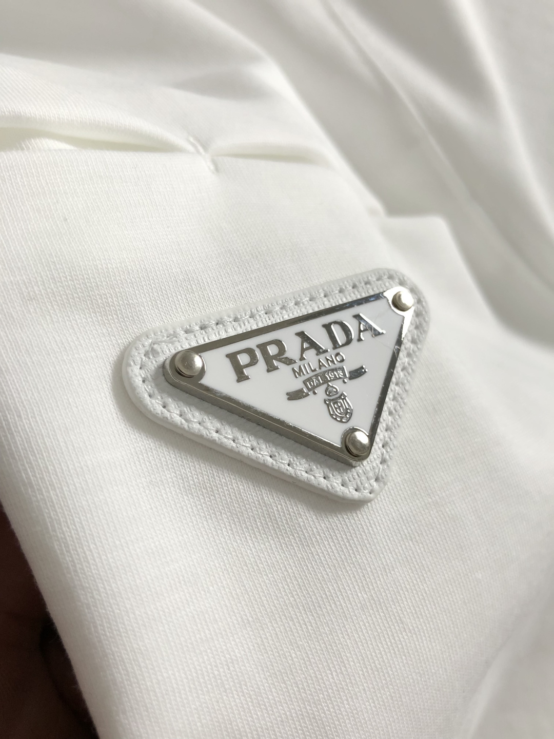 Prad*卡码拍小M-xxxl2026春夏短袖，以金属三角标口袋主调，巧妙融入后幅拼接面料元素，打破传统