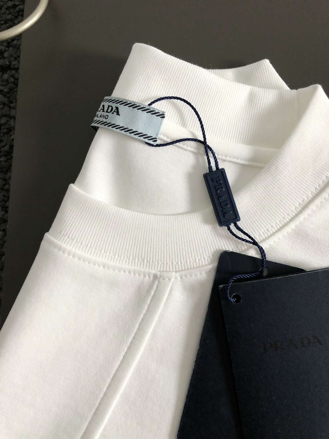 Prad*卡码拍小M-xxxl2026春夏短袖，以金属三角标口袋主调，巧妙融入后幅拼接面料元素，打破传统