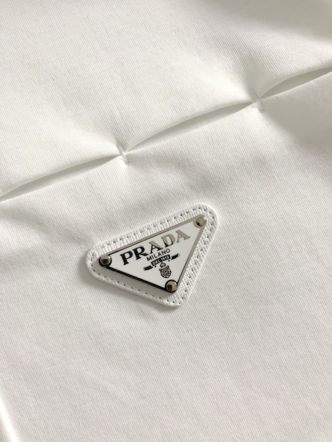 Prad*卡码拍小M-xxxl2026春夏短袖，以金属三角标口袋主调，巧妙融入后幅拼接面料元素，打破传统