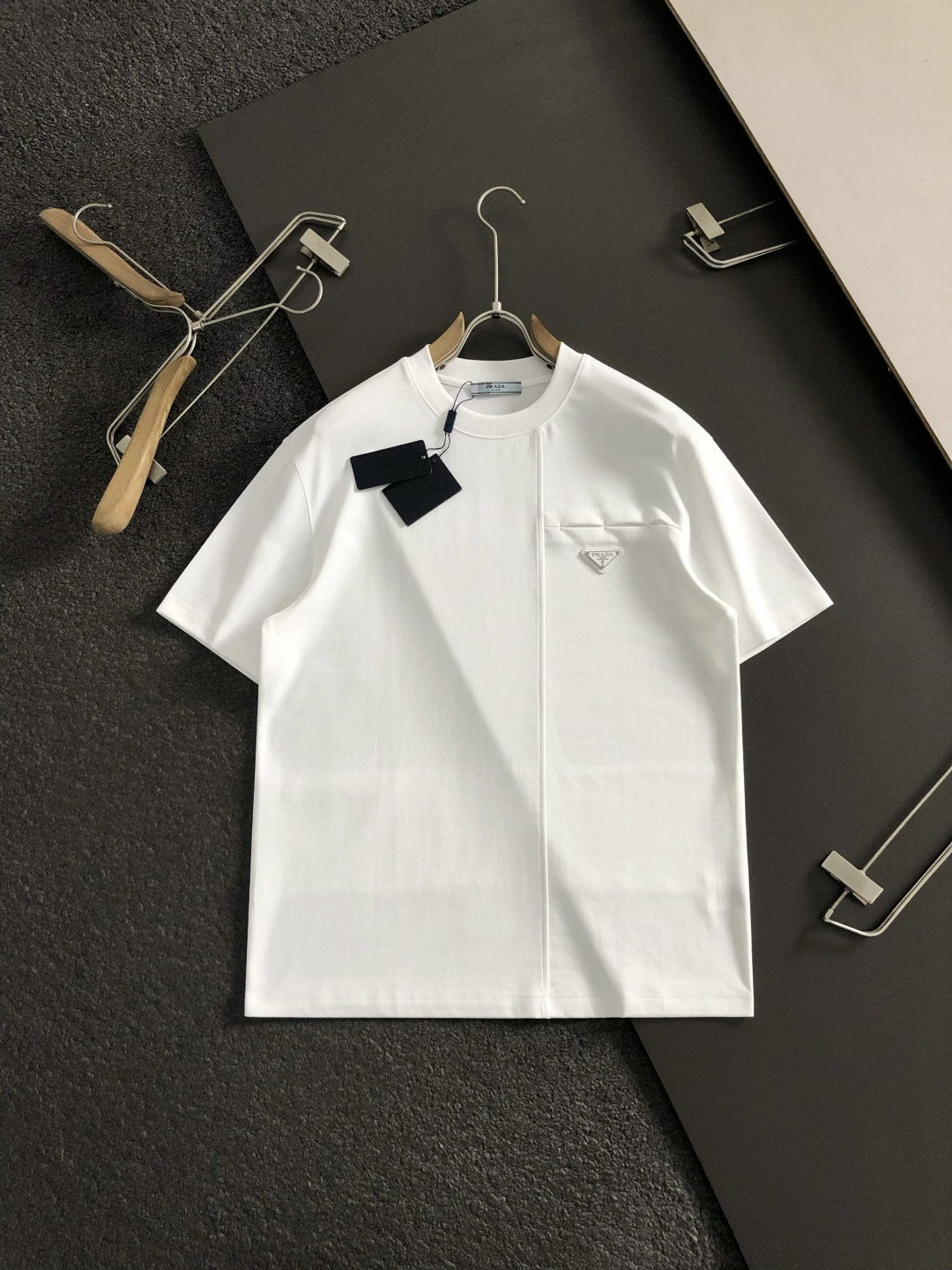 Prad*卡码拍小M-xxxl2026春夏短袖，以金属三角标口袋主调，巧妙融入后幅拼接面料元素，打破传统