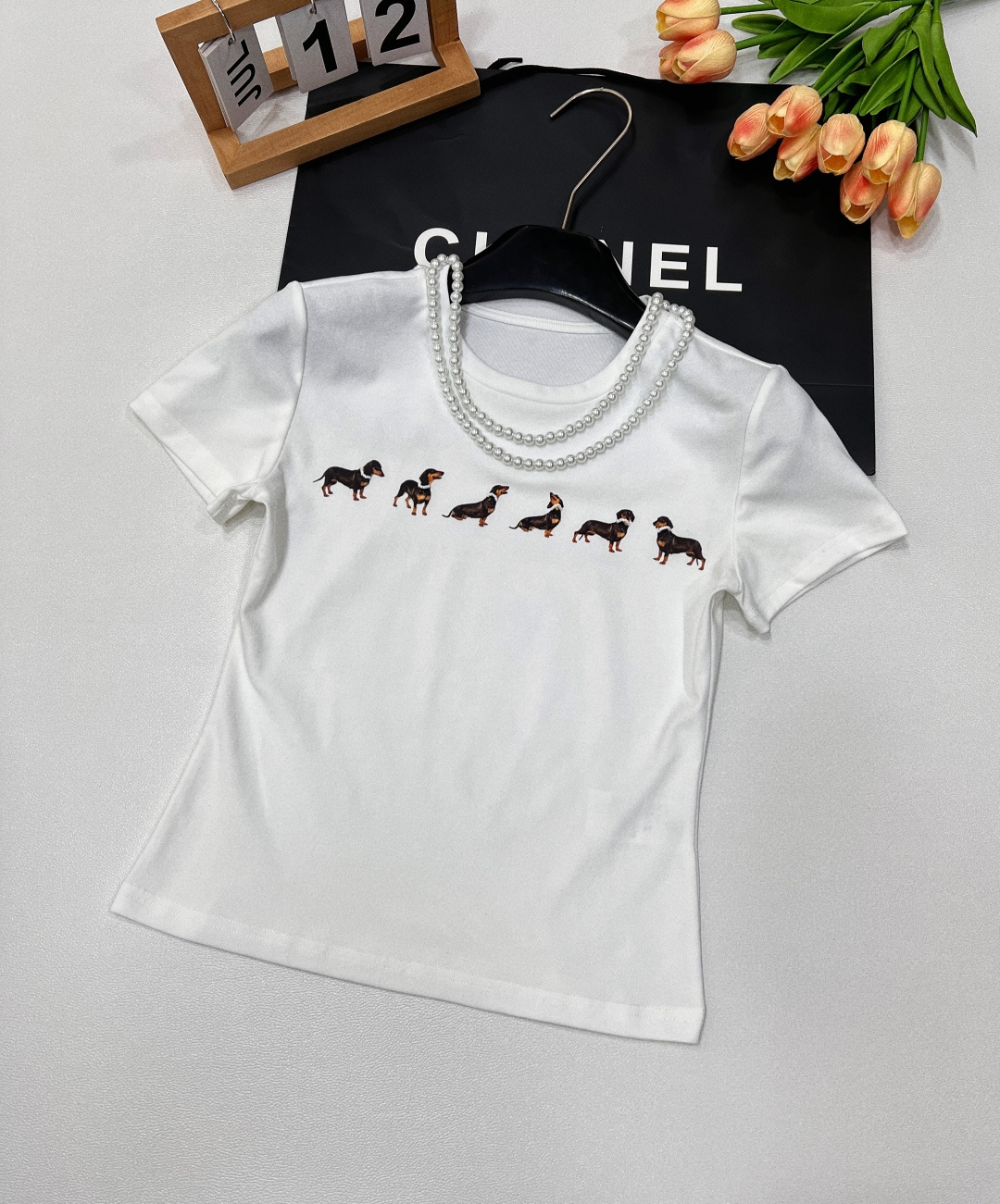 NO:328602,Markgong designer brand Jennie is the same style as pearl necklace dachshund dog slim short-sleeved T-shirt. This T-shirt is based on high-end combed cotton. It is delicate and skin-friendly and breathable. It incorporates a detachable pearl necklace to cleverly add elegant temperament and give more possibilities to wear. Every puppy is different. They all wear exquisite beaded necklaces. Unique design highlights the agility and fun of the pattern. Each puppy has a classic shoulder-mounted style, modifying the body to show proportions. It is slim and elastic, and the upper body is super slim. It is unique and fashionable and unique. Simple but full of street fashion. It is matched with cute dachshund dogs and exquisite waist-hugging tailoring. Once worn, it immediately gives the fresh and cool feeling of a Korean lady!  Size sml code, T-shirt,tees,t-shirt,necklace,alexander wang19860909Markgong设计师品牌Jennie同款配珍珠项链腊肠狗修身短袖T恤 此款T恤以高级精梳棉为基底 质感细腻且亲肤透气 融入了可拆卸的珍珠项链 巧妙增添优雅气质,同时赋予穿搭更多可能性 每只小狗都不一样 均佩戴精致串珠项链 独特设计 凸显图案的灵动与趣味每只小狗 经典正肩版型 ,修饰身材显比例.修身弹性,上身超级显瘦 别致又时髦有个性 简约却充满街头时尚感,搭配可爱的腊肠狗和收腰的精致剪裁,一穿上立马有那种韩国小姐姐的清新又酷感！ 尺码sml 编码,,T-shirt,tees，t-shirt,necklace,alexander wang,Women's clothing