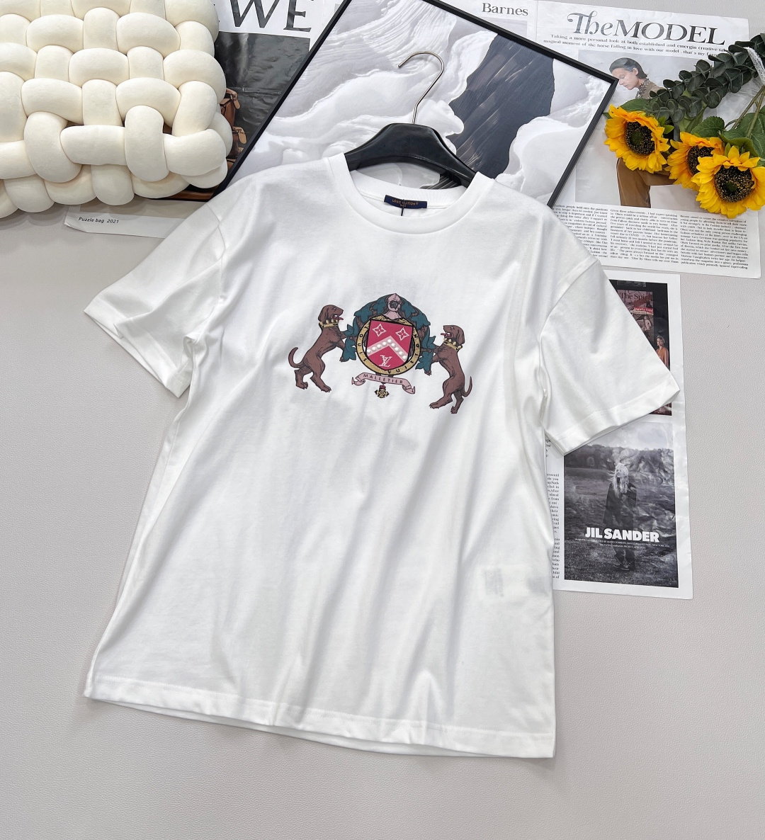 NO:414831,LOUIS VUITTON Pre-coll Double Dog Logo Pearl Short-Sleeve T-shirt This cotton T-shirt is inspired by Westminster dog walkers, embroidering embroidery and beads for the front Dog badge pattern, and embroidering the handwritten logo on the back of the eye-catching yarn. It is woven with fine number yarns, making the fabric light and breathable, and comfortable to wear. After combed, impurities and short fibers are removed; the yarn quality is high and the fabric structure is tight, so it has good wear resistance. In permeable water-based flat screen printing, the printing paste is printed onto the fabric through a flat screen, and then the permeability of the paste allows the dye to penetrate into the fibers of the fabric, thereby achieving the printing effect. Because the glue is water-soluble, it is easy to wash and improves the feel of the finished product.  The chest pattern is made of high-quality resin materials to ensure the gloss and durability of the beads. The shining imitation crystal is inlaid with key parts of the logo formed by the resin beads. The color of the imitation crystal is similar to that of the resin beads to create a harmonious and unified overall style; you can also choose contrasting colors to highlight the distinct personality and unique temperament. Size sml code l,,louis vuitton,T-shirt,tees,t-shirt,alexander wang19860909LOUIS VUITTON Pre-coll 双狗徽标珍珠短袖T恤 本款棉质T恤向威斯敏斯特遛狗一族采撷灵感,为正面谐趣Dog 徽章图案点缀刺绣和珠饰,并以醒目纱线刺绣后部的手写体标识. 采用细支数纱线织造,使得面料质地轻薄,透气性好,穿着舒适.经过精梳处理,去除杂质和短纤维；纱线品质较高,织物结构紧密,因此具有较好的耐穿性. 渗透水性平网印花制作,印花浆料通过平网版印刷到织物上,然后利用浆料的渗透性使染料渗透到织物的纤维中,从而实现印花效果.由于胶浆具有水溶性,因此易于洗除,能改善成品手感. 胸前图案选用高品质的树脂材料,确保珠饰的光泽度和耐用性.在树脂珠饰构成的标识的关键部位镶嵌闪耀的仿水晶.仿水晶的颜色与树脂珠饰相近的色调,以营造出和谐统一的整体风格；也可以选择对比鲜明的颜色,以突出鲜明个性和独特气质. 尺码sml 编码l,,louis vuitton,T-shirt,tees，t-shirt,alexander wang,Women's clothing