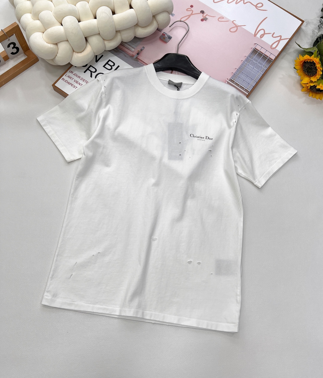 NO:421911,DIOR25SS new ripped old lily of the valley printed round neck short sleeves, fabric made of pure cotton natural fiber has good hygroscopicity, strong breathability, soft and comfortable properties. Cotton fabrics are usually suitable for summer wear and can help keep the body dry and comfortable. Yarn alternately passes horizontally and vertically to form a simple cross structure; it has good elasticity and wear resistance. Decorated with the full name logo and lily of the valley printed pattern, imported powder slurry printing process, which achieves a delicate color transition through special slurry formula and precision processing, and reduces the color layer of the petals. For tulle fabrics, light diffuser is added to the powder slurry to make the printing area appear matte matte matte, which contrasts with the transparent background.  The fabric is specially pretreated to create a natural wear and fading effect. During the sewing process, special sewing techniques and stitch density are used to enhance the durability and natural feeling of the short-sleeved sleeves. A combination of machine wear or manual scratching is used to create slight wear marks on the surface of the ready-made garment to increase the authenticity of the antique effect. Round neck short-sleeved T-shirts are reprinted on the neckline and cuff design, and special sewing methods or reinforcement treatments are used to ensure the durability and comfort of these parts. Standard casual round neck short-sleeved sleeves usually adopt a classic round neck design, with a moderate neck size, neither too tight nor too loose, and can well show the wearer's neckline lines. The same style for men and women, three standards are complete!  Size xssml encoding,dior,T-shirt,tees,t-shirt,alexander wang19860909DIOR25SS新款破洞做旧铃兰印花圆领短袖,纯棉天然纤维制作的面料,具有吸湿性好、透气性强、柔软舒适等特性.棉质面料通常适合夏季穿着,可以帮助保持身体干爽和舒适.纱线在水平和垂直方向上交替穿过,形成简单的交叉结构；具有较好的弹性和耐磨性. 饰以全称标识与铃兰印花图案 进口粉浆印花工艺制作,通过特殊浆料配方与精密加工实现细腻色彩过渡,还原花瓣的色泽层次.针对薄纱面料,粉浆添加光扩散剂,使印花区域呈现哑光雾面,与透明底色形成对比. 面料经过特殊的预处理,以营造出自然的磨损和褪色效果.缝制过程中,采用特殊的缝纫技术和线迹密度,以增强短袖的耐用性和自然感.采用机器磨损或手工刮擦两者结合的方法,在成衣表面制造出轻微的磨损痕迹,增加仿旧效果的真实感. 圆领短袖T恤在领口和袖口的设计上开版还原,采用特殊的缝制方法或加固处理,以确保这些部位的耐用性和舒适度.标准休闲圆领短袖通常采用经典的圆领设计,领口大小适中,既不会过于紧绷也不会过于宽松,能够很好地展现穿着者的颈部线条.男女同款,三标齐全！ 尺码xssml 编码,,dior,T-shirt,tees，t-shirt,alexander wang,Women's clothing