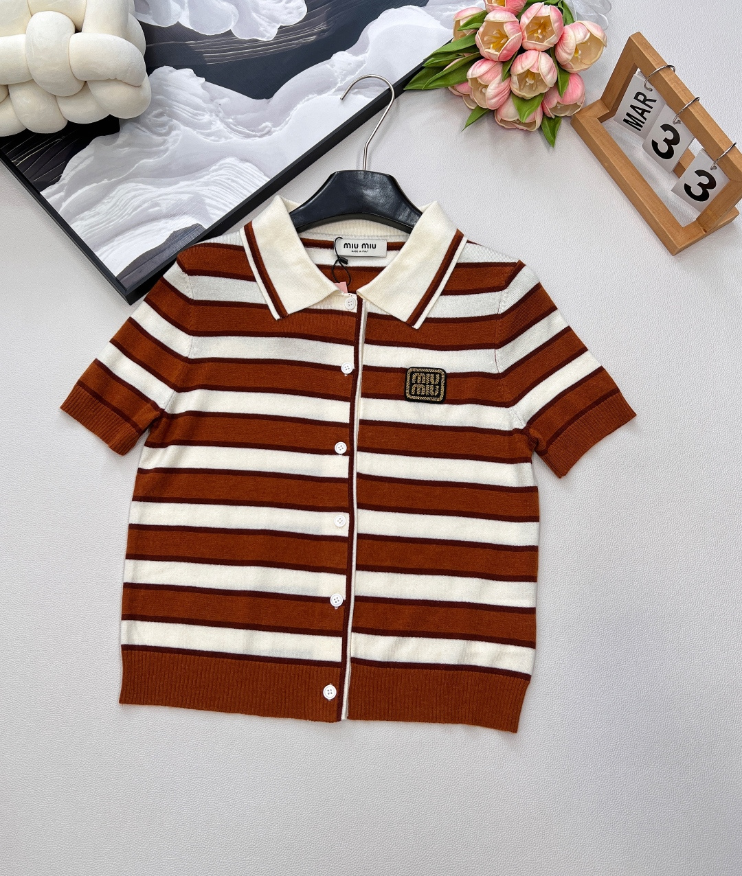 NO:432225,Miumiu's new contrasting striped letters cardigan, the magic of wearing fashionable on the body, customized wool yarn. This contrasting striped cardigan directly welds the 'college noble sense' on the body. The contrasting striped stripes come with a retro filter, and the brown and white/yellow hidden blue color combination is superb, like weaving sunshine and coffee into the clothes. The lapel design is neat and age-reducing, and the single-breasted hides a trick. If you want to expose your skin, open two pieces. Take the lazy feeling~ The letters on the chest are the soul!  It is so exquisite that it is low-key to announce 'I am a fashionable player'. The knitted fabric is soft and skin-friendly, and the short-sleeved tailoring is suitable for the season. It is refreshing and layered with small suspenders. Whether it is high-waisted pants, it is also very stylish to wear it. Whether it is a retro senior girl with a short skirt or a sweet and cool girl, it can revive the outfit in one piece, and it is definitely a 'treasure of the wardrobe'. The fashionable delicate eyes are closed, and it falls in love with three standards once you wear it, and the two colors are outstanding. Size sml is written by M,,miumiu, skirts, T-shirt, alexander wang19860909Miumiu新款撞色条纹字母章开衫,把时髦穿在身上的魔法,定制的羊毛纱线.缪缪这款撞色条纹开衫 直接把“学院贵气感”焊在身上 撞色条纹自带复古滤镜,棕白/黄藏蓝配色超绝,像把阳光和咖啡都织进衣服里 翻领设计利落又减龄,单排扣藏着小心机,想露肤就开两颗,慵懒感拿捏～ 胸前字母章仔是灵魂！精致到不行,低调宣告“我是时髦玩家” 针织面料软糯亲肤,短袖剪裁适配季节,单穿清爽、搭小吊带叠穿也超有范儿. 不管是配高腰裤走复古学姐风,还是搭短裙当甜酷辣妹,一件就能盘活穿搭,妥妥“衣柜宝藏担当” 时髦精闭眼冲,穿一次就爱上三标齐全,两色出 尺码sml 编M,,miumiu,skirts,T-shirt,alexander wang,Women's clothing