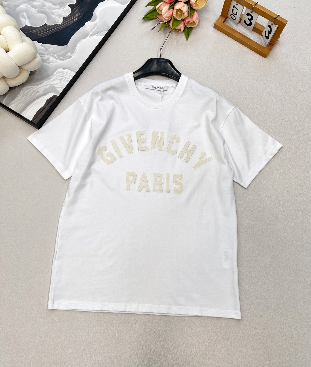 NO:441607,GIVENCHYGVC zigzag patch letter round neck short-sleeved T-shirt. It uses 15S fine cotton plain patterns, g; matched with threaded 32S double yarn pull-up frame, 300g.15S is a relatively thick yarn, used to make thicker and durable fabrics. The fabric made of pure cotton natural fiber has the characteristics of good hygroscopicity, strong breathability, soft and comfortable. Cotton fabrics are usually suitable for summer wear and can help keep the body dry and comfortable. The yarn alternately passes horizontally and vertically to form a simple cross structure; it has good elasticity and wear resistance.  The zigzag stitching process of vertical patch material is matched with zigzag stitching; the three-dimensionality and precision of the logo are enhanced through material comparison and stitching details. The hard ribbon with fine vertical stripes on the surface is soft and has strong wear resistance; it forms a dynamic outline around the edge through serrated stitching, and the sewing patch is fixed on the base fabric to enhance the handmade texture, touch and visual contrast. The casual round neck knitted short-sleeved H-shaped style, the shoulder drop refers to the natural sagging of the shoulder lines, which connects with the body lines, creating a relaxed and comfortable feeling. Use dark thread techniques to gather the back; the flat back piece is ironed according to the body shape to form a body piece. The same style of men and women, three standards are complete, large-scale products are available. Size xssml, given, T-shirt,tees, t-shirt,alexander wang19860909GIVENCHYGVC之字贴布字母圆领短袖T恤.采用15S精棉平纹,g；搭配螺纹32S双纱拉架,300g.15S是相对较粗的纱线,用于制作较为厚实和耐用的面料.纯棉天然纤维制作的面料,具有吸湿性好、透气性强、柔软舒适等特性.棉质面料通常适合夏季穿着,可以帮助保持身体干爽和舒适.纱线在水平和垂直方向上交替穿过,形成简单的交叉结构；具有较好的弹性和耐磨性. 竖纹贴布材质搭配之字形缝线工艺；通过材质对比与缝线细节强化标识的立体感和精致度.表面有细密竖条纹的硬挺缎带,光泽柔和,耐磨性强；通过锯齿状线迹围绕边缘形成动态轮廓,缝制贴布固定在基底面料上,提升手工质感,触觉与视觉反差. 休闲款圆领针织短袖H版型,落肩是指肩部线条自然下垂,与身体线条相衔接,营造出一种轻松舒适的感觉.以暗线手法归拢后背；将平面的后衣片,按体形归烫成立体衣片.男女同款,三标齐全,大货出 尺码xssml 编,,givenchy,T-shirt,tees，t-shirt,alexander wang,Women's clothing