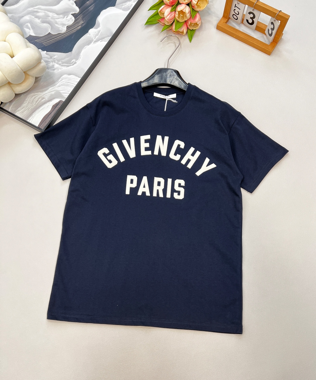 NO:441615,GIVENCHYGVC zigzag patch letter round neck short-sleeved T-shirt. It uses 15S fine cotton plain patterns, g; with threaded 32S double yarn pull-up frame, 300g.15S is a relatively thick yarn, used to make thicker and durable fabrics. The fabric made of pure cotton natural fiber has the characteristics of good hygroscopicity, strong breathability, soft and comfortable. Cotton fabrics are usually suitable for summer wear and can help keep the body dry and comfortable. The yarn alternately passes horizontally and vertically to form a simple cross structure; it has good elasticity and wear resistance.  The zigzag stitching process of vertical patch material is matched with zigzag stitching; the three-dimensionality and precision of the logo are enhanced through material comparison and stitching details. The hard ribbon with fine vertical stripes on the surface is soft and has strong wear resistance; it forms a dynamic outline around the edge through serrated stitching, and the sewing patch is fixed on the base fabric to enhance the handmade texture, touch and visual contrast. The casual round neck knitted short-sleeved H-shaped style, the shoulder drop refers to the natural sagging of the shoulder lines, which connects with the body lines, creating a relaxed and comfortable feeling. Use dark thread techniques to gather the back; the flat back piece is ironed according to the body shape to form the body piece. Size smlXL woven, givenchy, T-shirt,tees, t-shirt,alexander wang19860909GIVENCHYGVC之字贴布字母圆领短袖T恤.采用15S精棉平纹,g；搭配螺纹32S双纱拉架,300g.15S是相对较粗的纱线,用于制作较为厚实和耐用的面料.纯棉天然纤维制作的面料,具有吸湿性好、透气性强、柔软舒适等特性.棉质面料通常适合夏季穿着,可以帮助保持身体干爽和舒适.纱线在水平和垂直方向上交替穿过,形成简单的交叉结构；具有较好的弹性和耐磨性. 竖纹贴布材质搭配之字形缝线工艺；通过材质对比与缝线细节强化标识的立体感和精致度.表面有细密竖条纹的硬挺缎带,光泽柔和,耐磨性强；通过锯齿状线迹围绕边缘形成动态轮廓,缝制贴布固定在基底面料上,提升手工质感,触觉与视觉反差. 休闲款圆领针织短袖H版型,落肩是指肩部线条自然下垂,与身体线条相衔接,营造出一种轻松舒适的感觉.以暗线手法归拢后背；将平面的后衣片,按体形归烫成立体衣片. 尺码smlXL 编,,givenchy,T-shirt,tees，t-shirt,alexander wang,Women's clothing